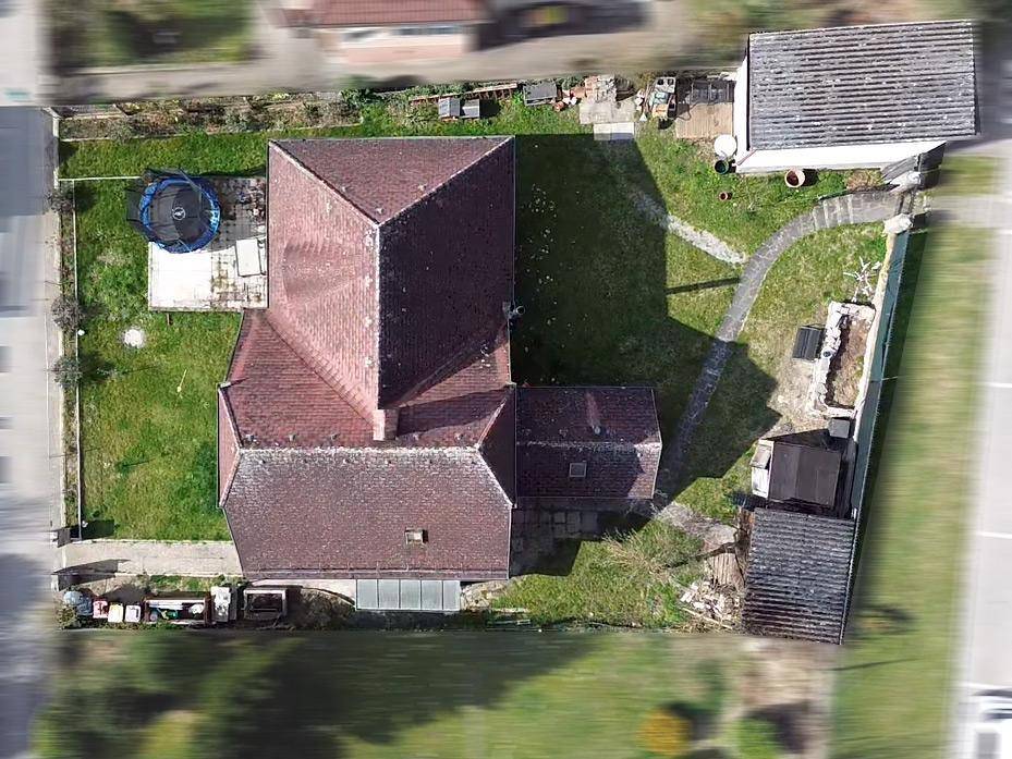 Draufsicht des Hauses mit Garten, Trampolin und gepflastertem Weg im Außenbereich.