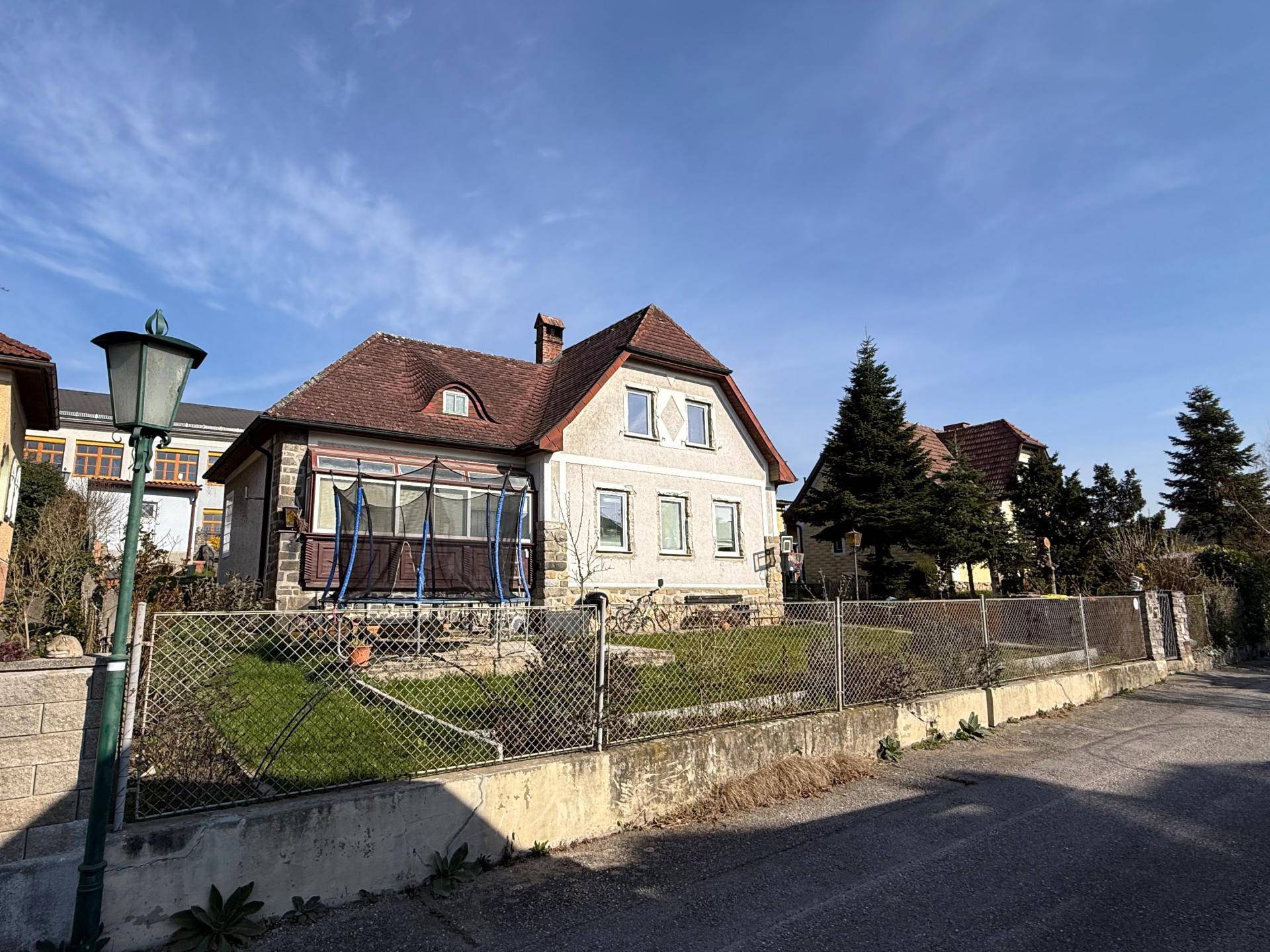 Ansicht des Hauses von der Straße mit Vorgarten und Laterne bei blauem Himmel.