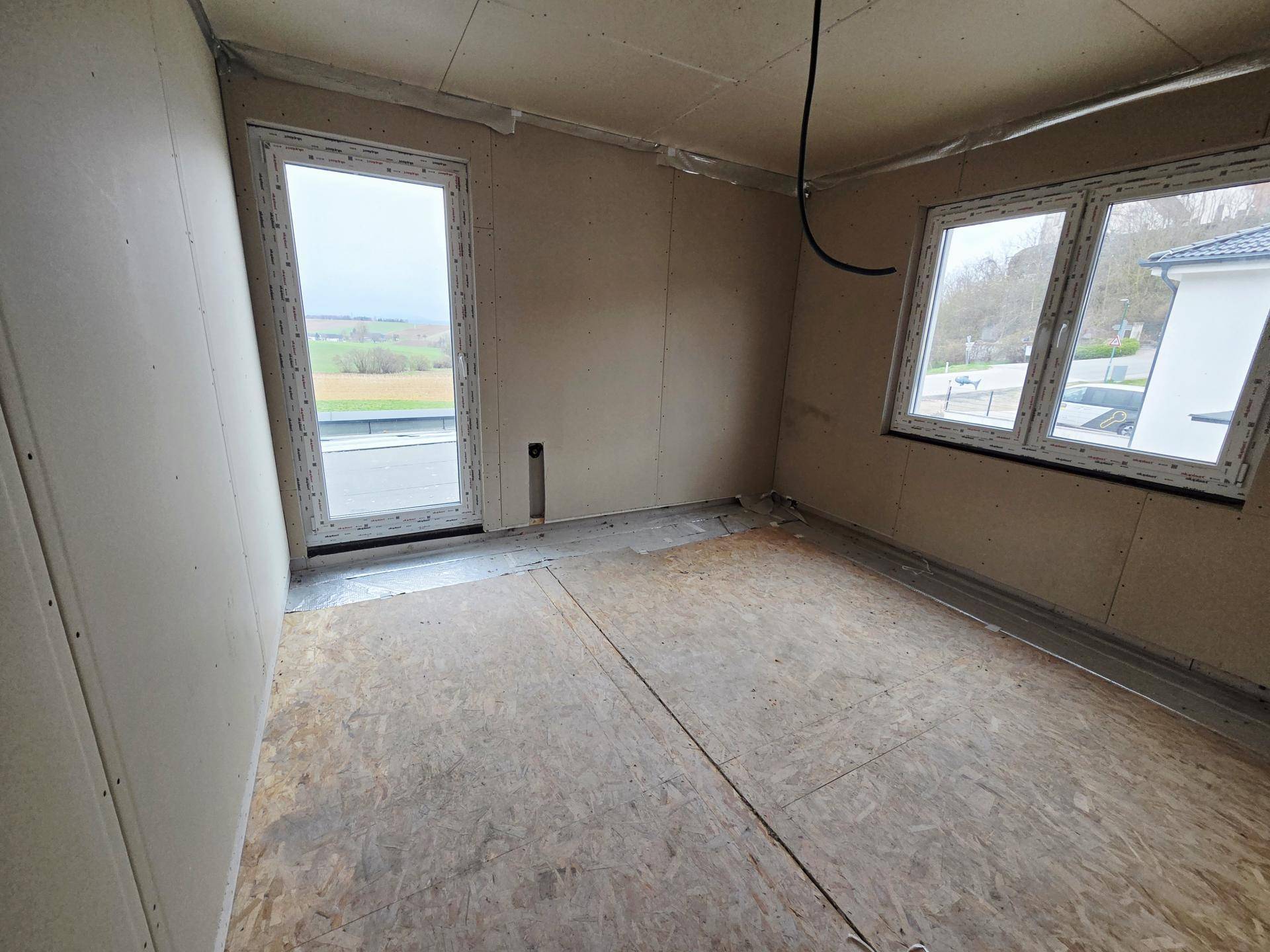 Unfertiges Schlafzimmer mit Zugang zu einem Außenbereich und weitem Ausblick in die Landschaft.
