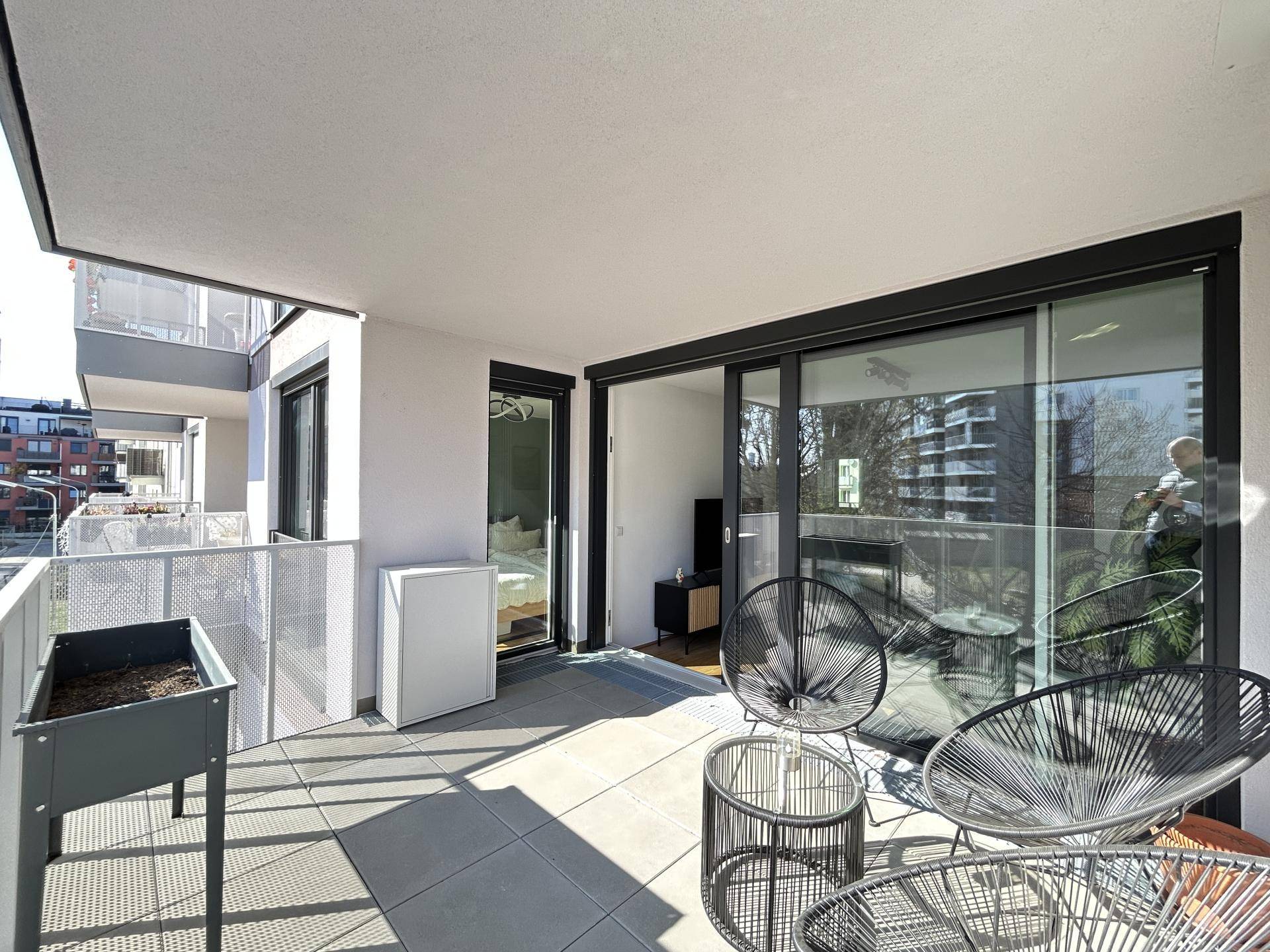 Großer Balkon mit Fliesenboden, Metallgeländer und Blick auf die umliegenden Gebäude.