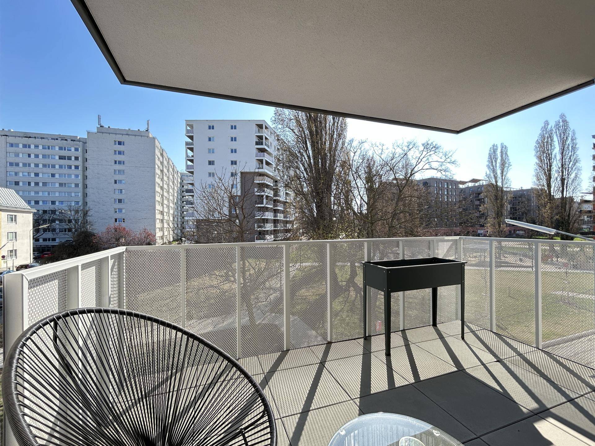 Balkon mit Metallgeländer, Pflanzkübel und weitem Blick auf die Stadtlandschaft.
