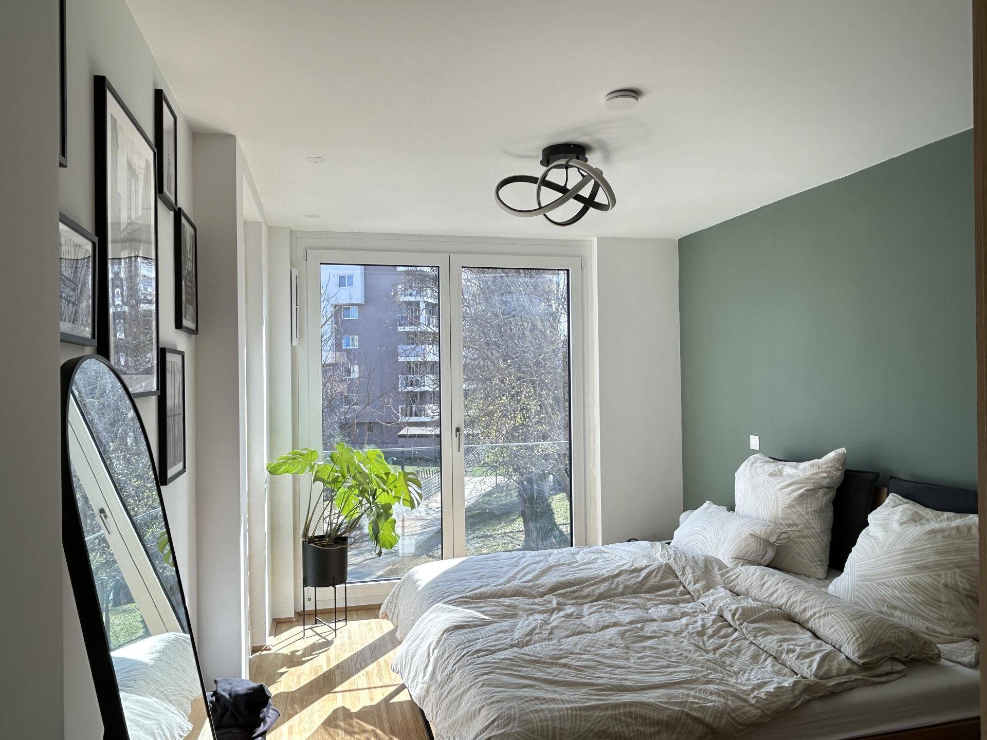 Schlafzimmer mit großem Fenster, Doppelbett und Blick ins Grüne.
