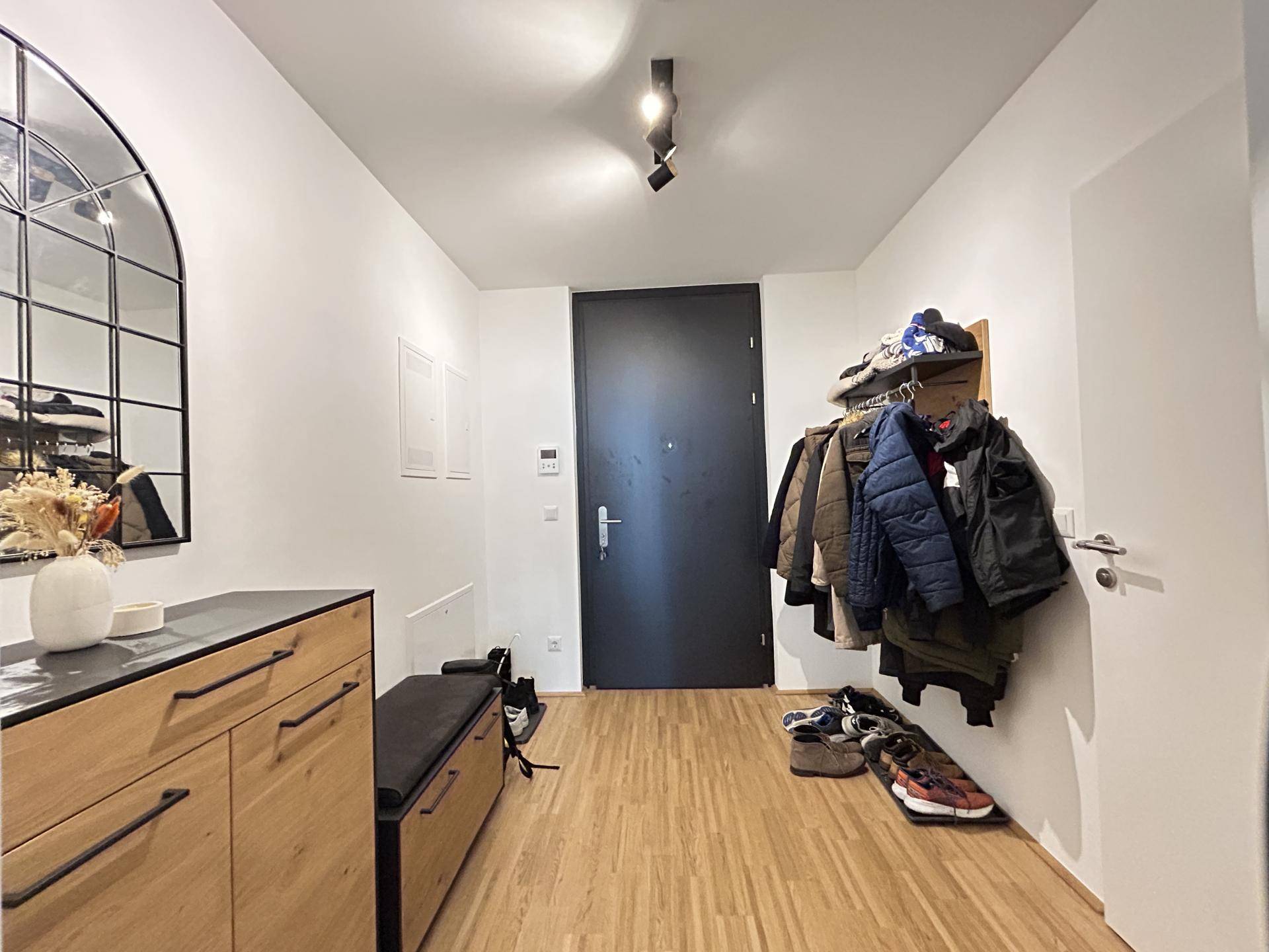 Heller Eingangsbereich mit Garderobe, Spiegel und Holzboden.