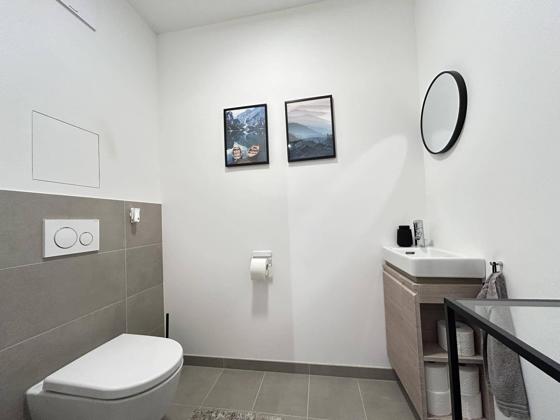 Separate Gästetoilette mit wandhängendem WC und kleinem Waschbecken.