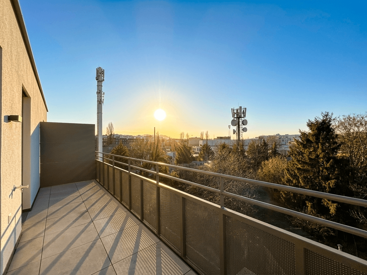 Sonniger Balkon mit weitem Blick über die Stadtlandschaft und die umliegenden Bäume.