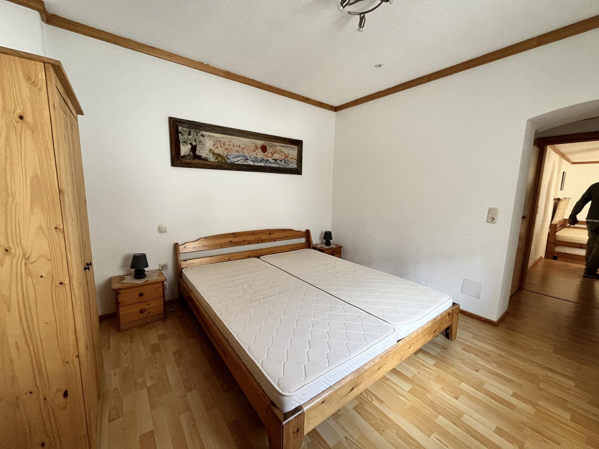 Helles Schlafzimmer mit Holzmöbeln, Parkettboden und einem Doppelbett.