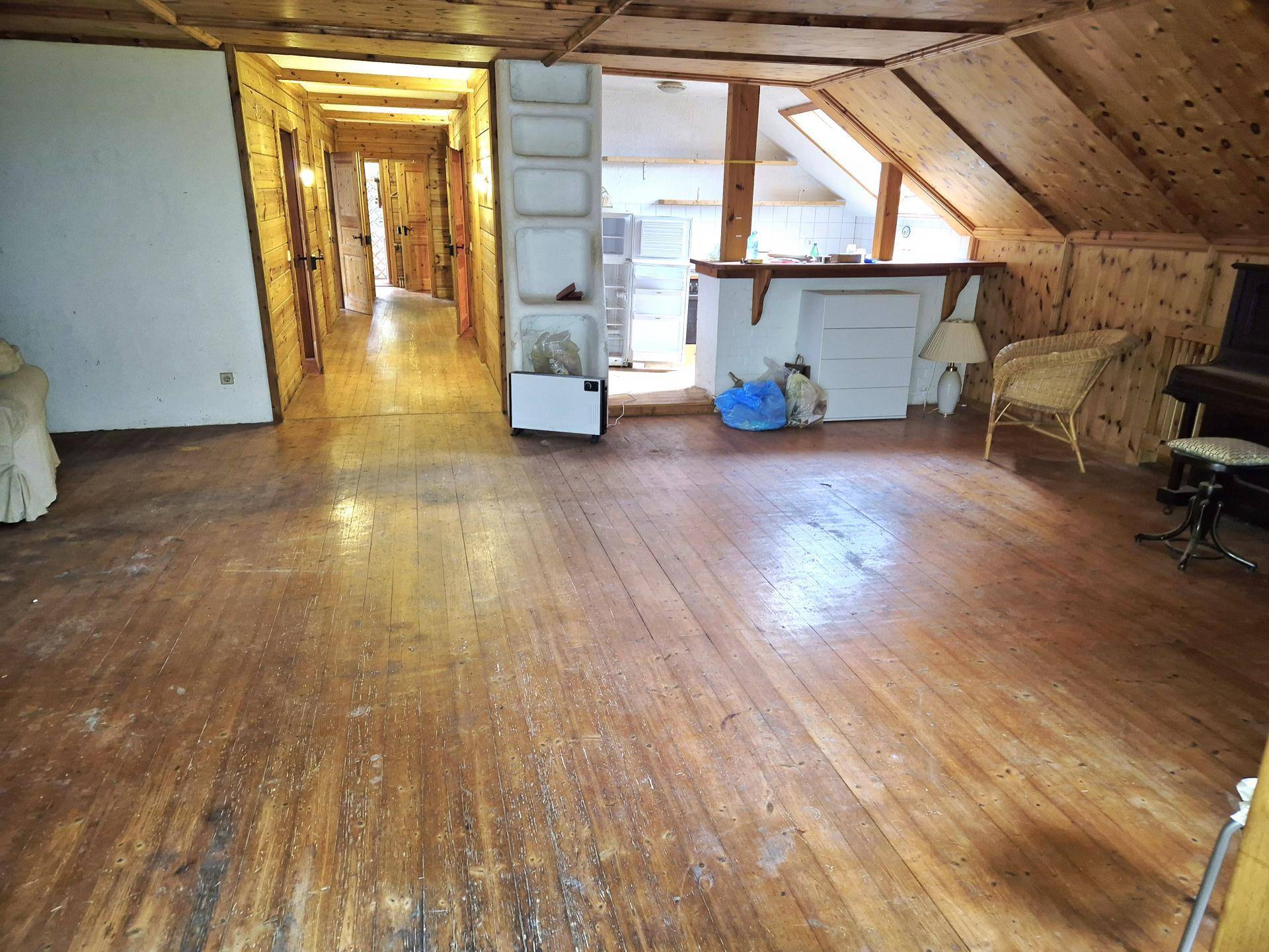 Geräumiger Wohnbereich im Dachgeschoss mit Holzboden, Holzverkleidung und Bar.