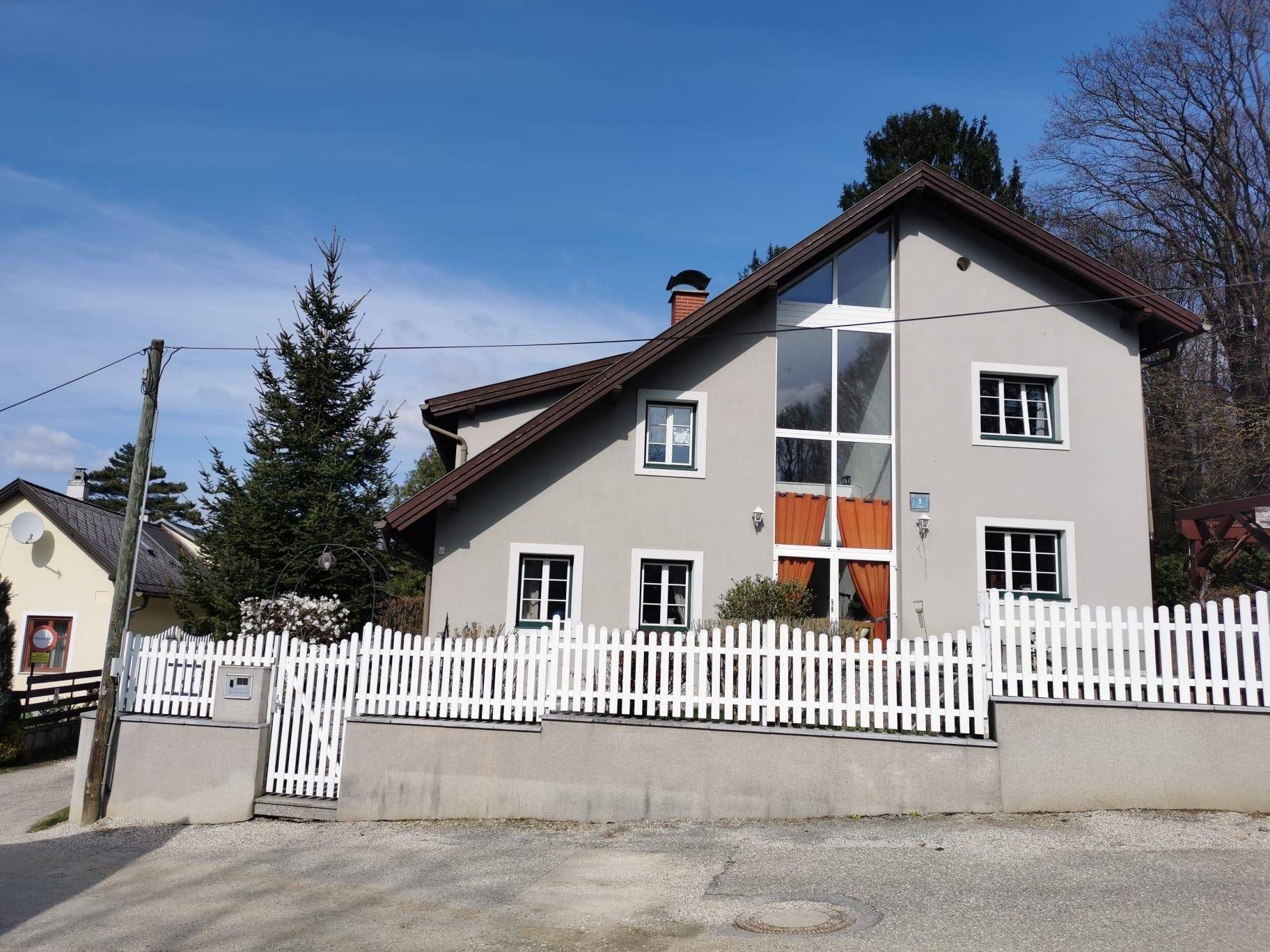 Vorderansicht des Einfamilienhauses mit großem Giebelfenster und weißem Lattenzaun.