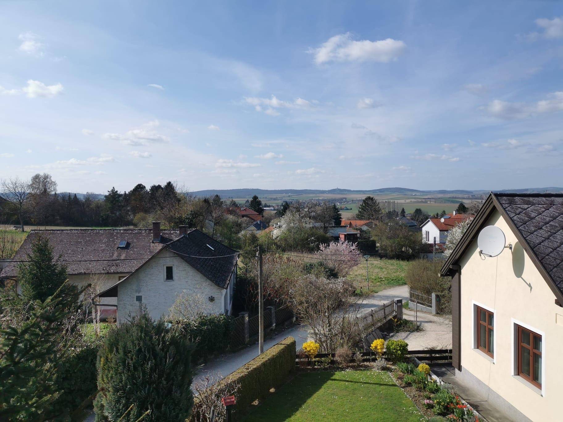 Weitläufiger Blick über die ländliche Umgebung mit weiteren Häusern und grünen Feldern.