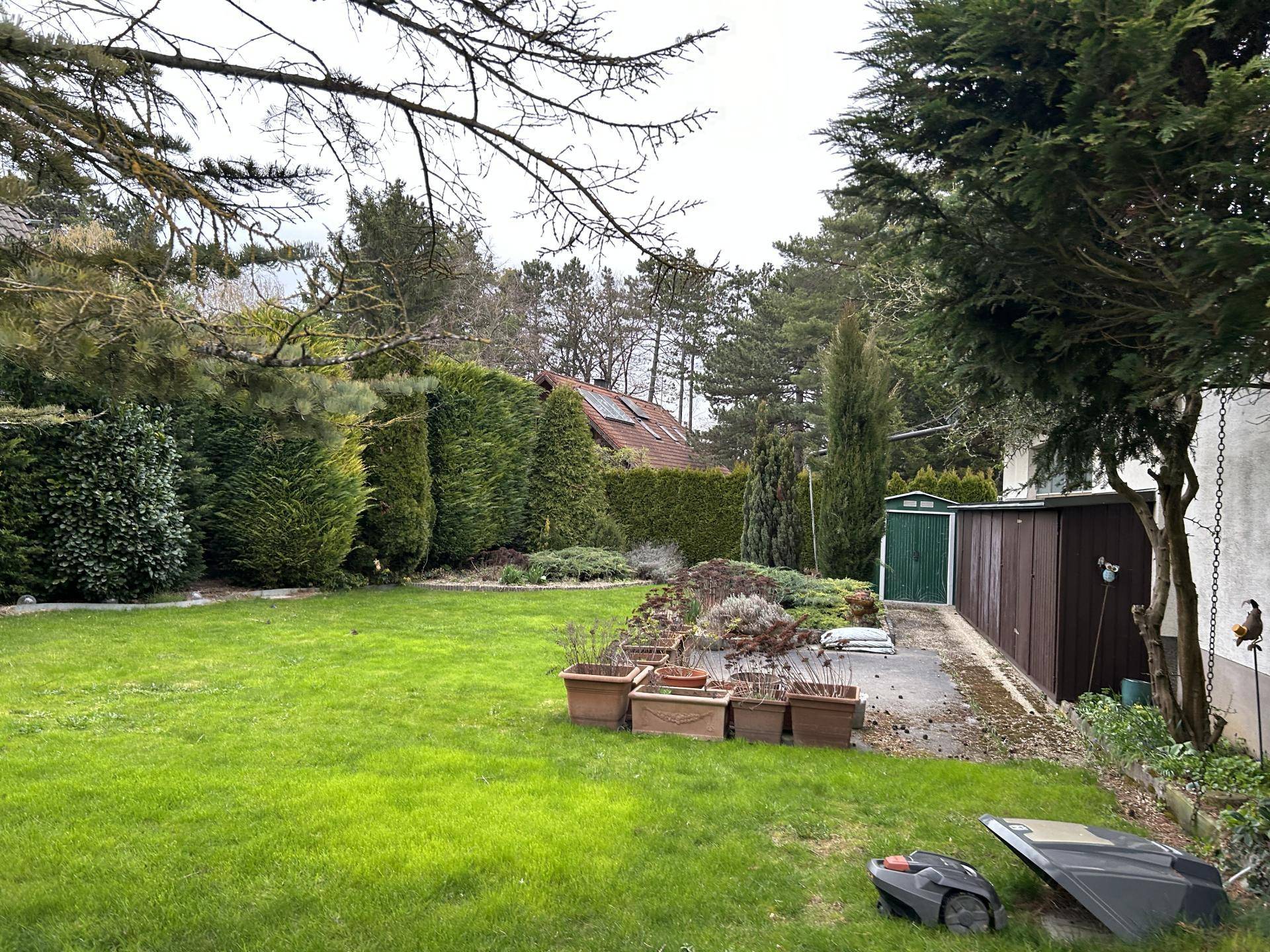 Großer Garten mit Rasenfläche, Sträuchern und einem Geräteschuppen neben dem Haus.