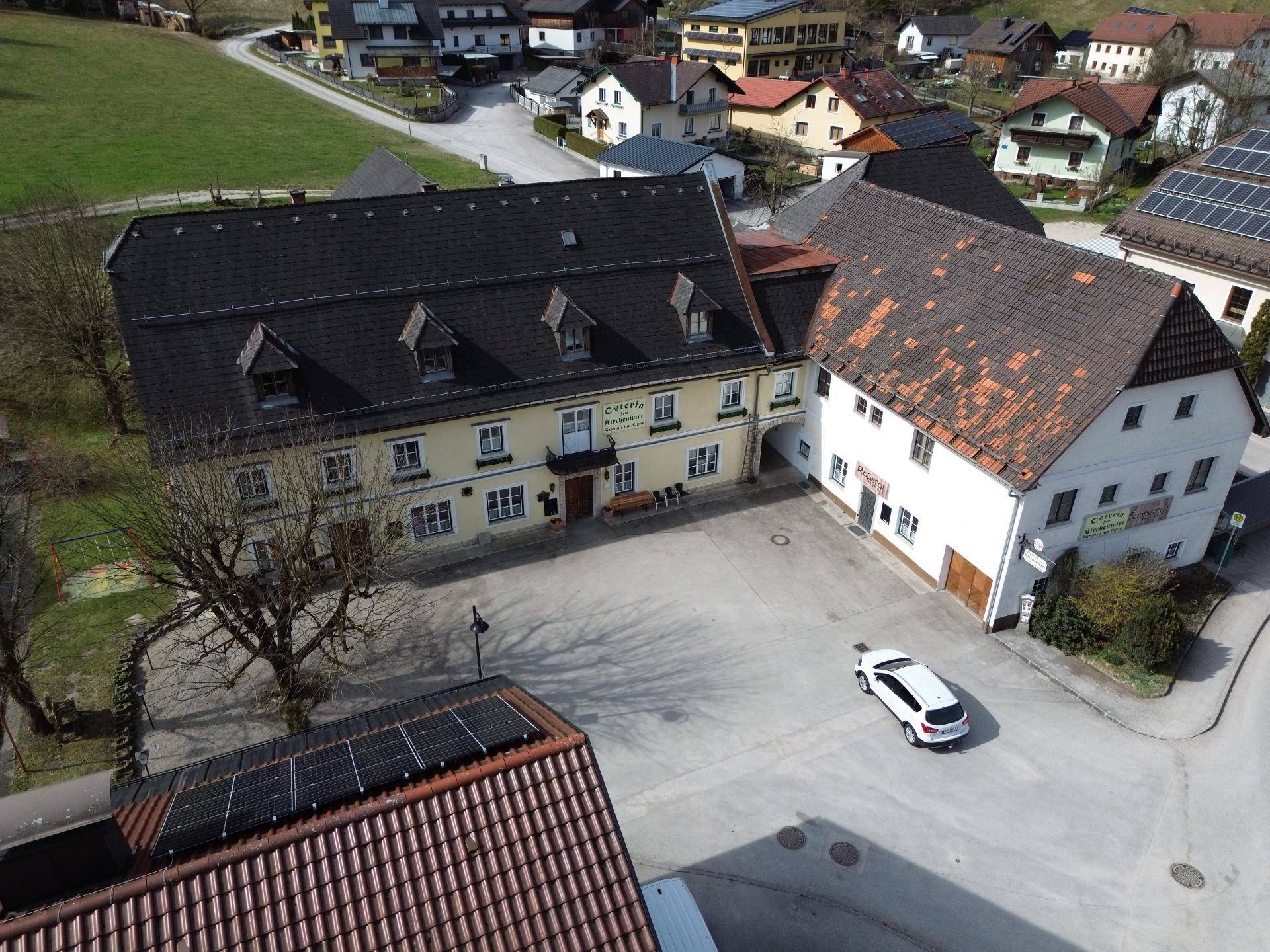 Luftaufnahme des Anwesens mit umliegenden Häusern und einem Parkplatz.