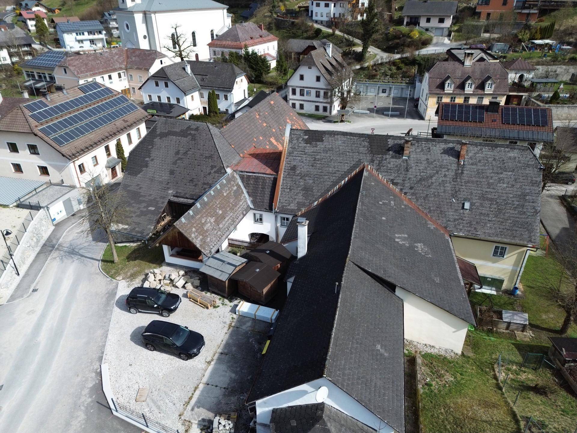 Luftaufnahme des Anwesens mit mehreren Dächern und umliegender Bebauung.