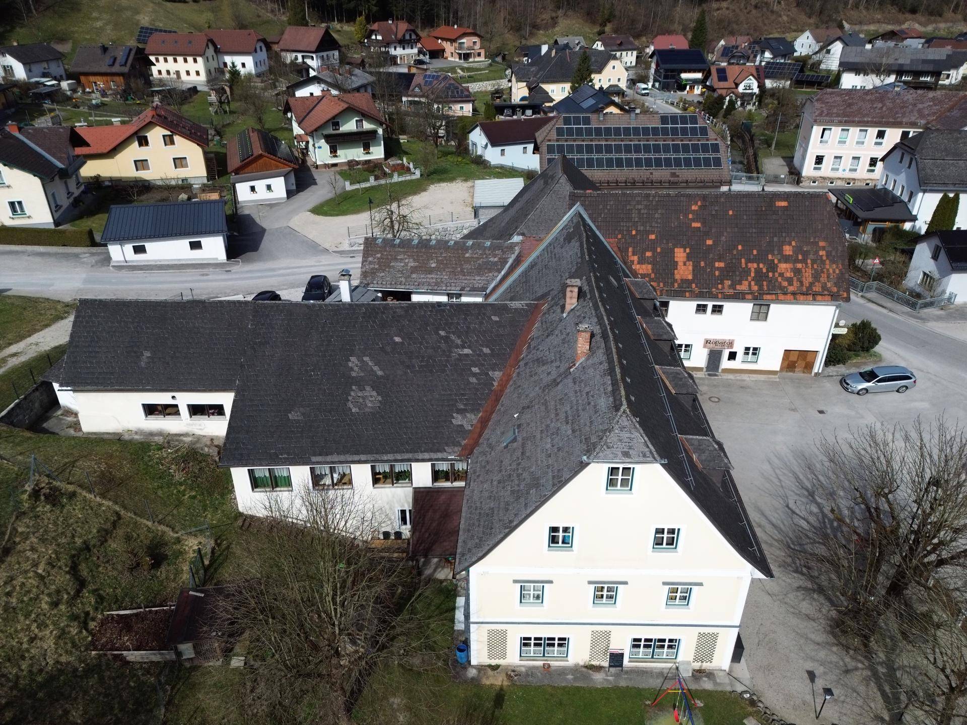 Weitläufige Luftaufnahme des Anwesens mit umliegenden Häusern und viel Grün.