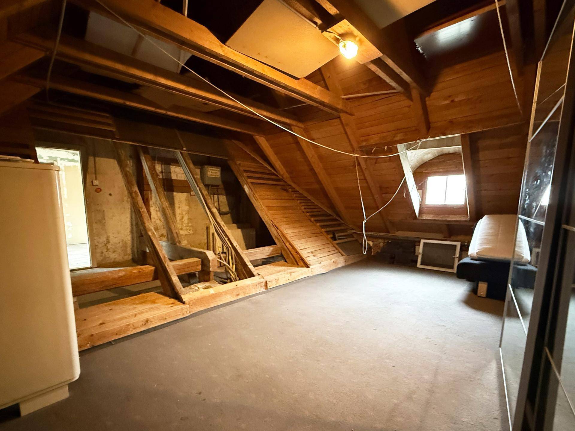 Dachboden mit sichtbarer Holzkonstruktion und Dachschrägen, bietet Stauraum oder Ausbaupotenzial.