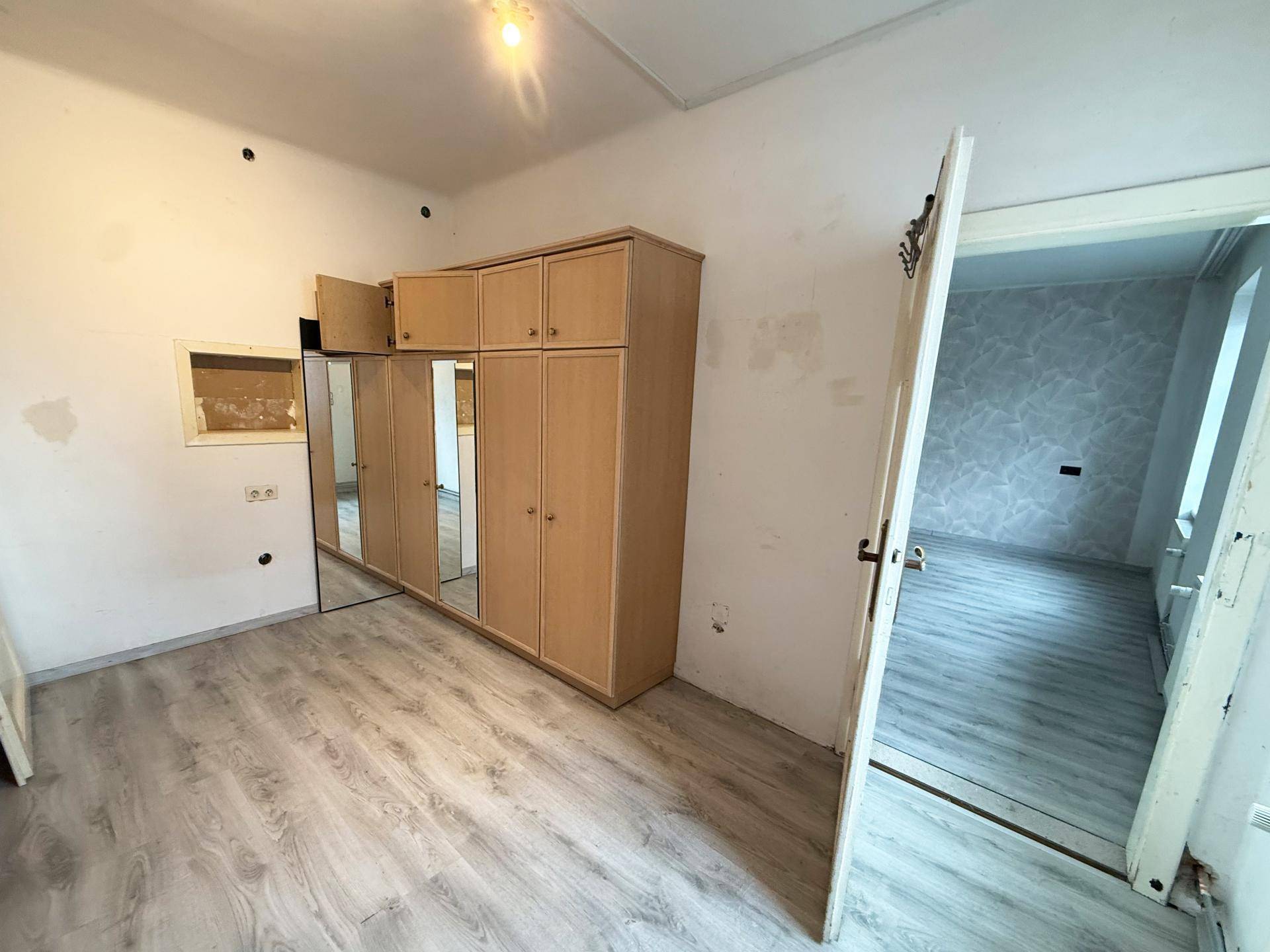 Schlafzimmer mit Laminatboden und einem großen Kleiderschrank mit Spiegeltüren.