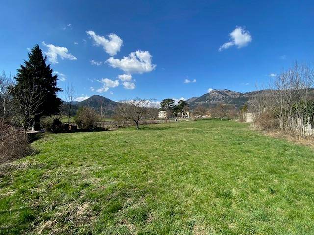 Offenes Grundstück mit grüner Wiese und Panoramablick auf die Berge und den weiten Himmel.