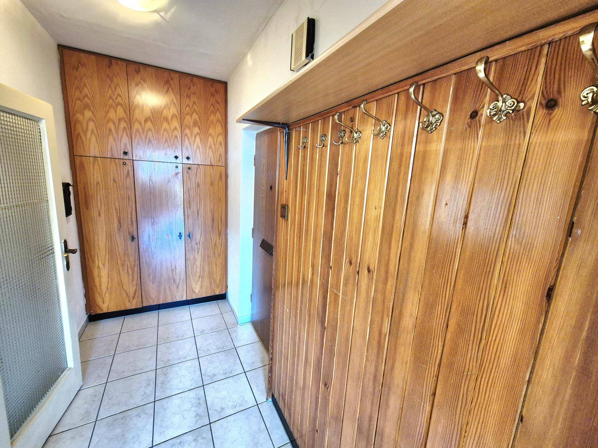 Eingangsbereich mit praktischen Holzschränken und Garderobe, bietet viel Stauraum.