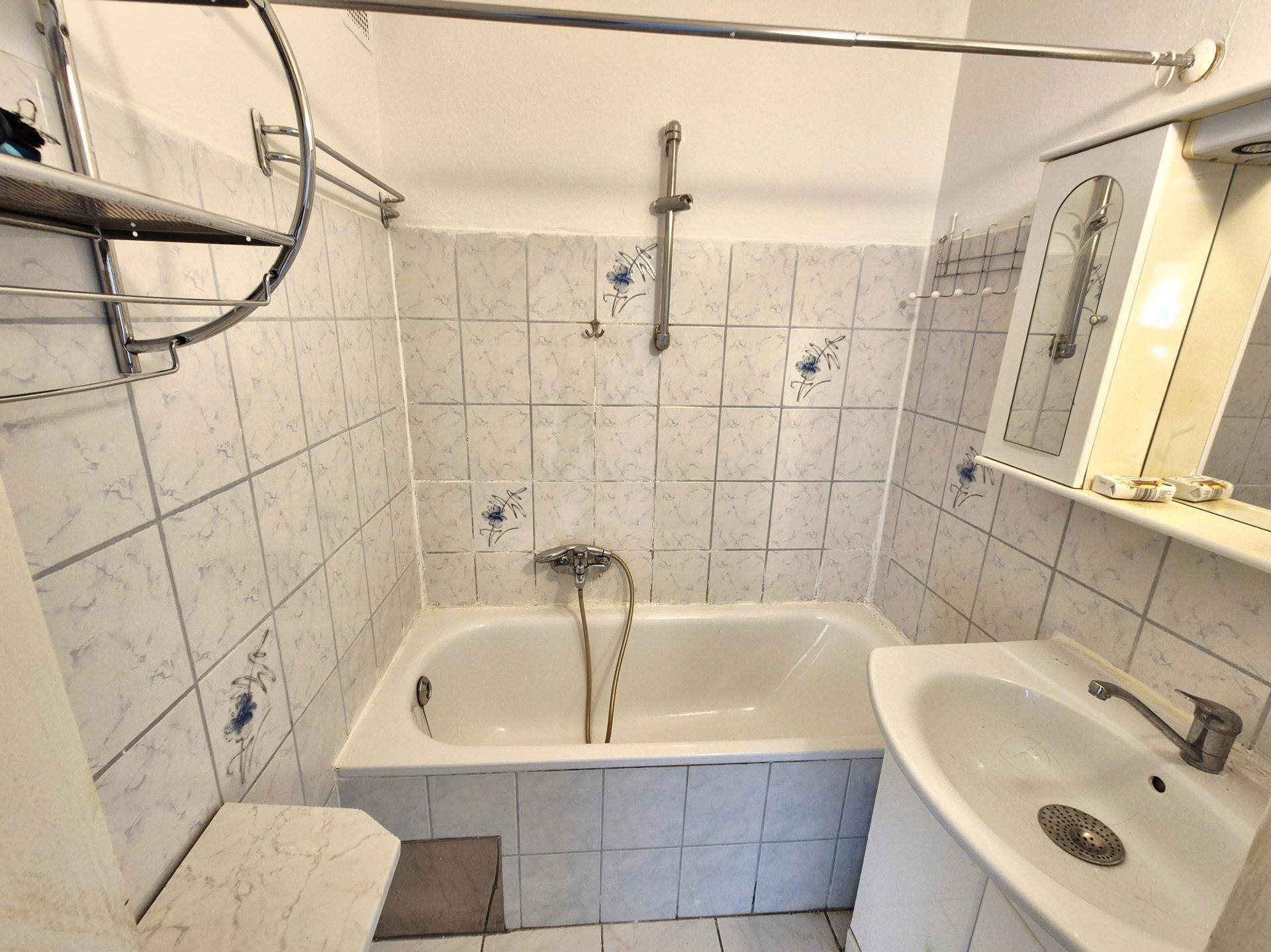 Gefliestes Badezimmer mit Badewanne, Waschbecken und Spiegelschrank, funktional eingerichtet.