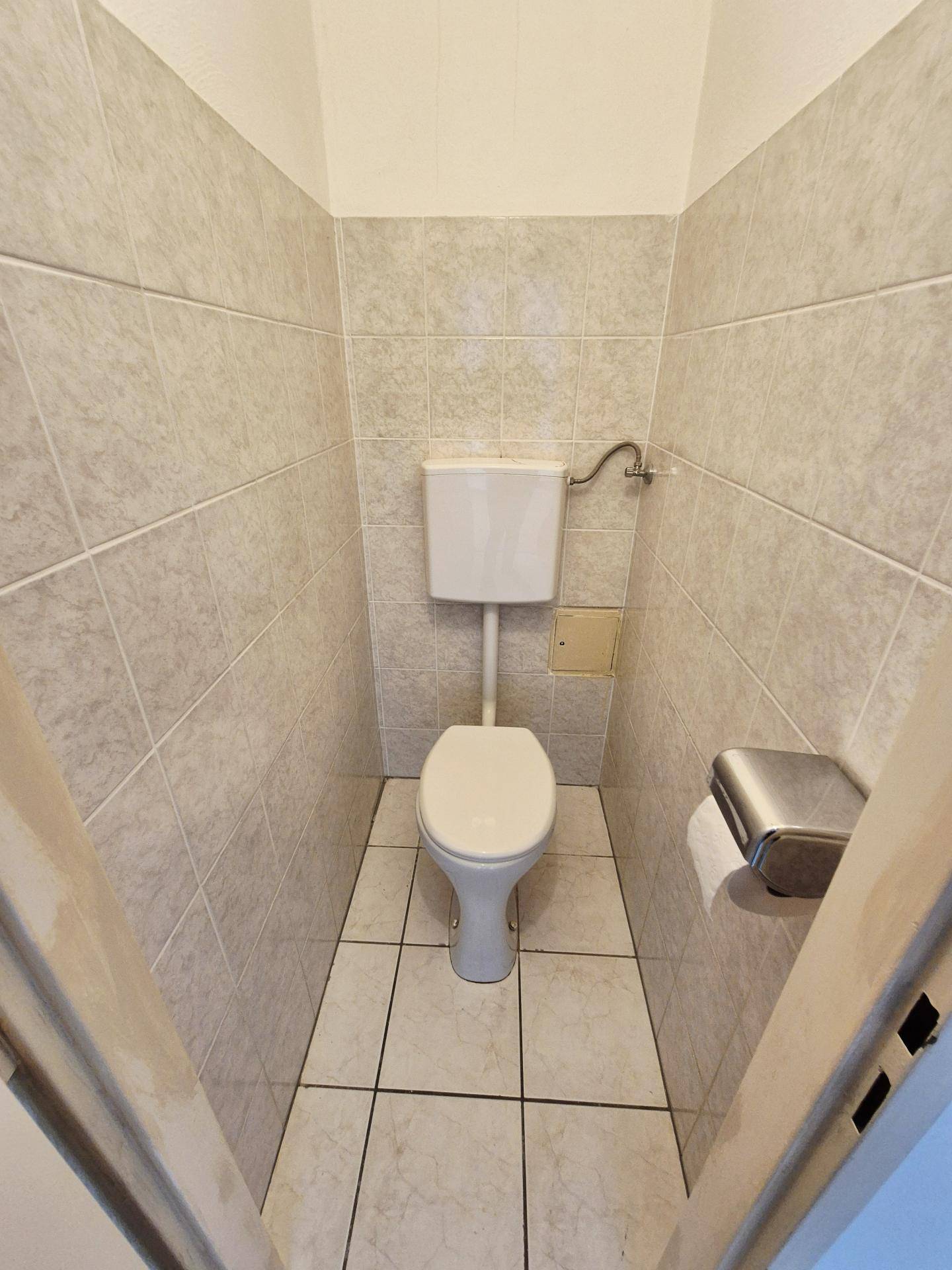 Kleines Gäste-WC mit hellen Fliesen und Standardausstattung, sauber und funktional.