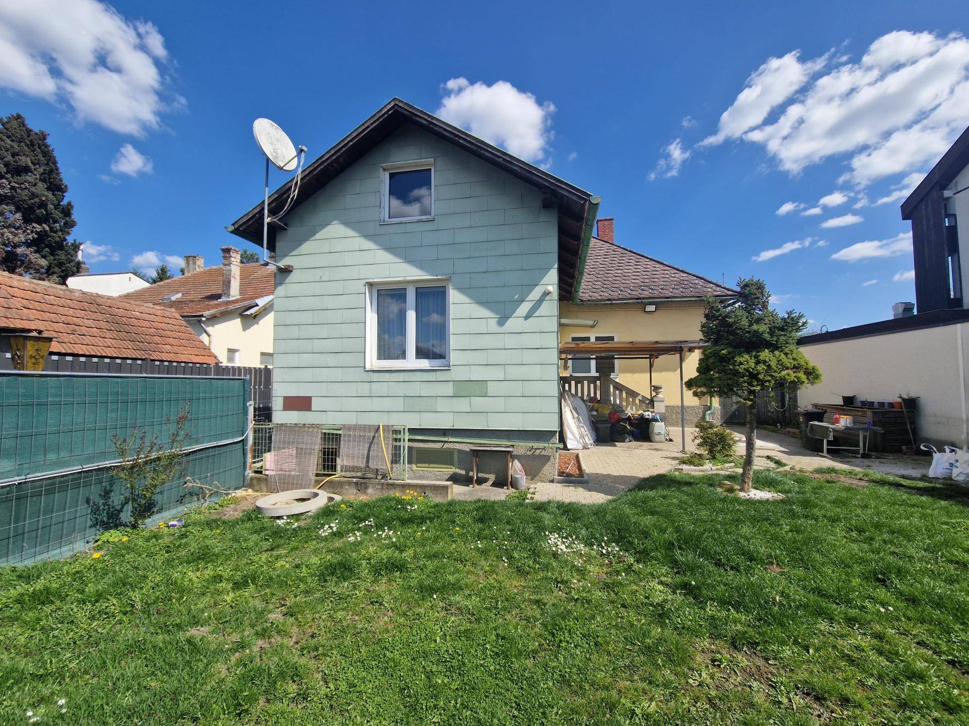 Rückansicht des Hauses mit hellgrüner Fassade und einem gepflegten Gartenbereich.