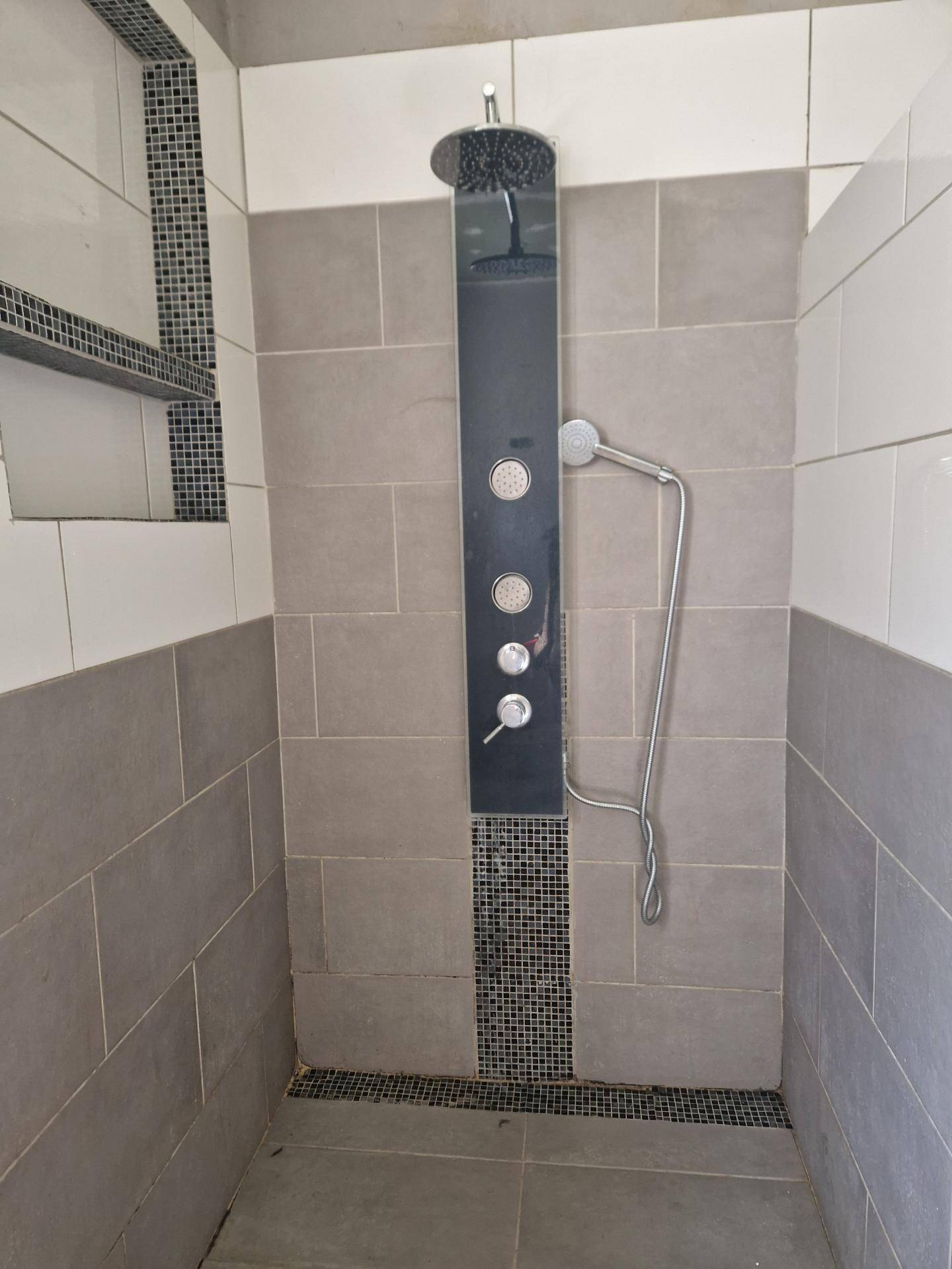 Moderne Duschkabine mit grauen und weißen Fliesen sowie einer Regendusche.