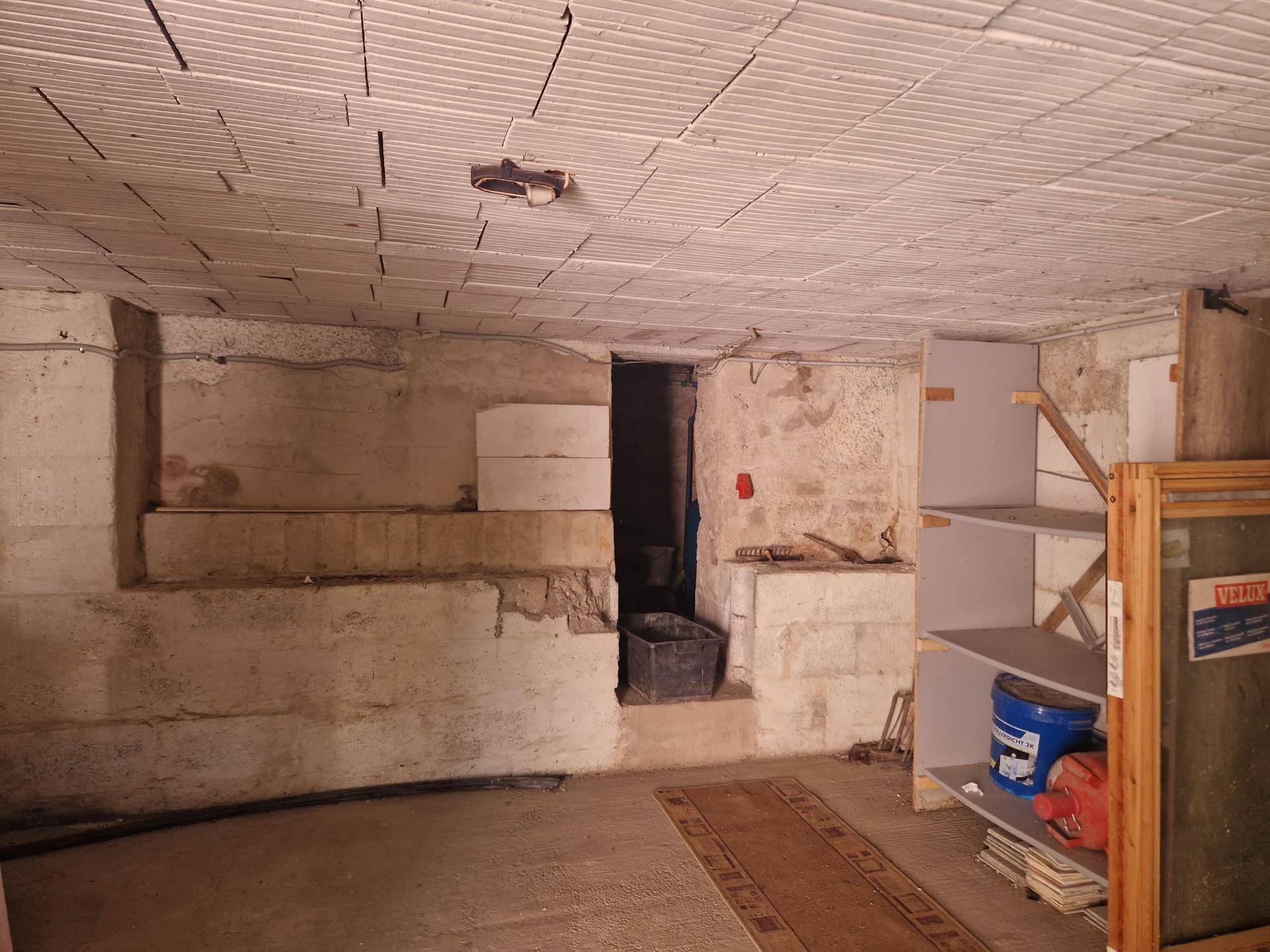 Unausgebauter Kellerraum mit Betonwänden, Regalen und Lagerflächen.
