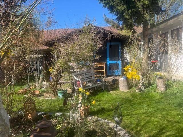 Idyllischer Gartenbereich mit Rasen, einer Holzbank und einem kleinen blauen Gartenhaus.