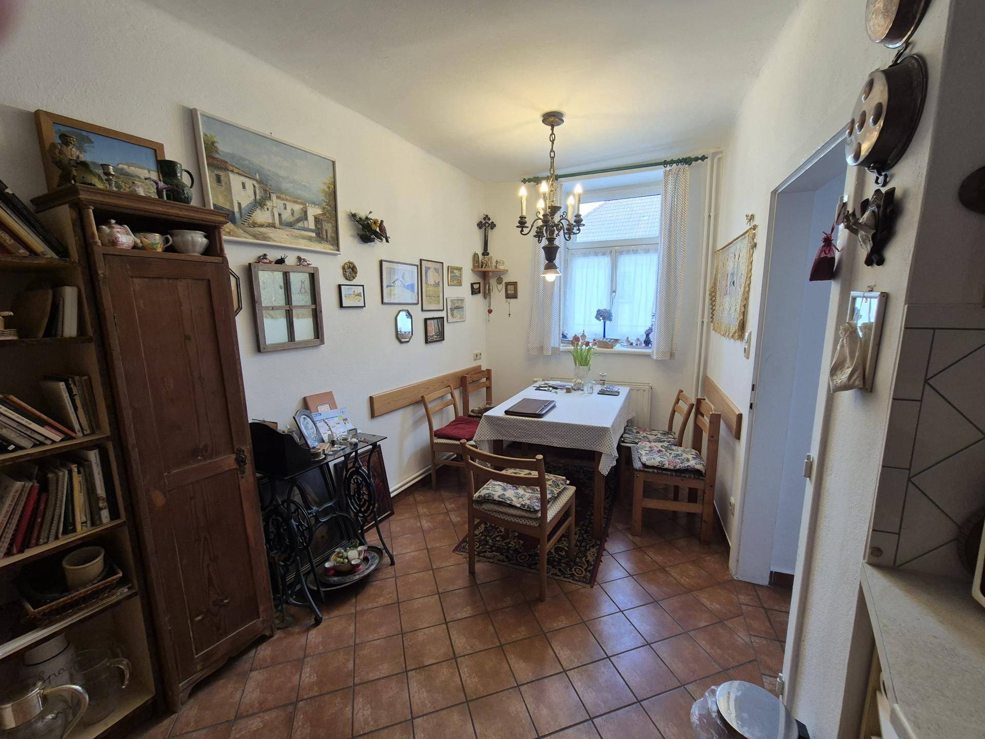 Esszimmer mit Fliesenboden, Esstisch und traditioneller Dekoration an den Wänden.