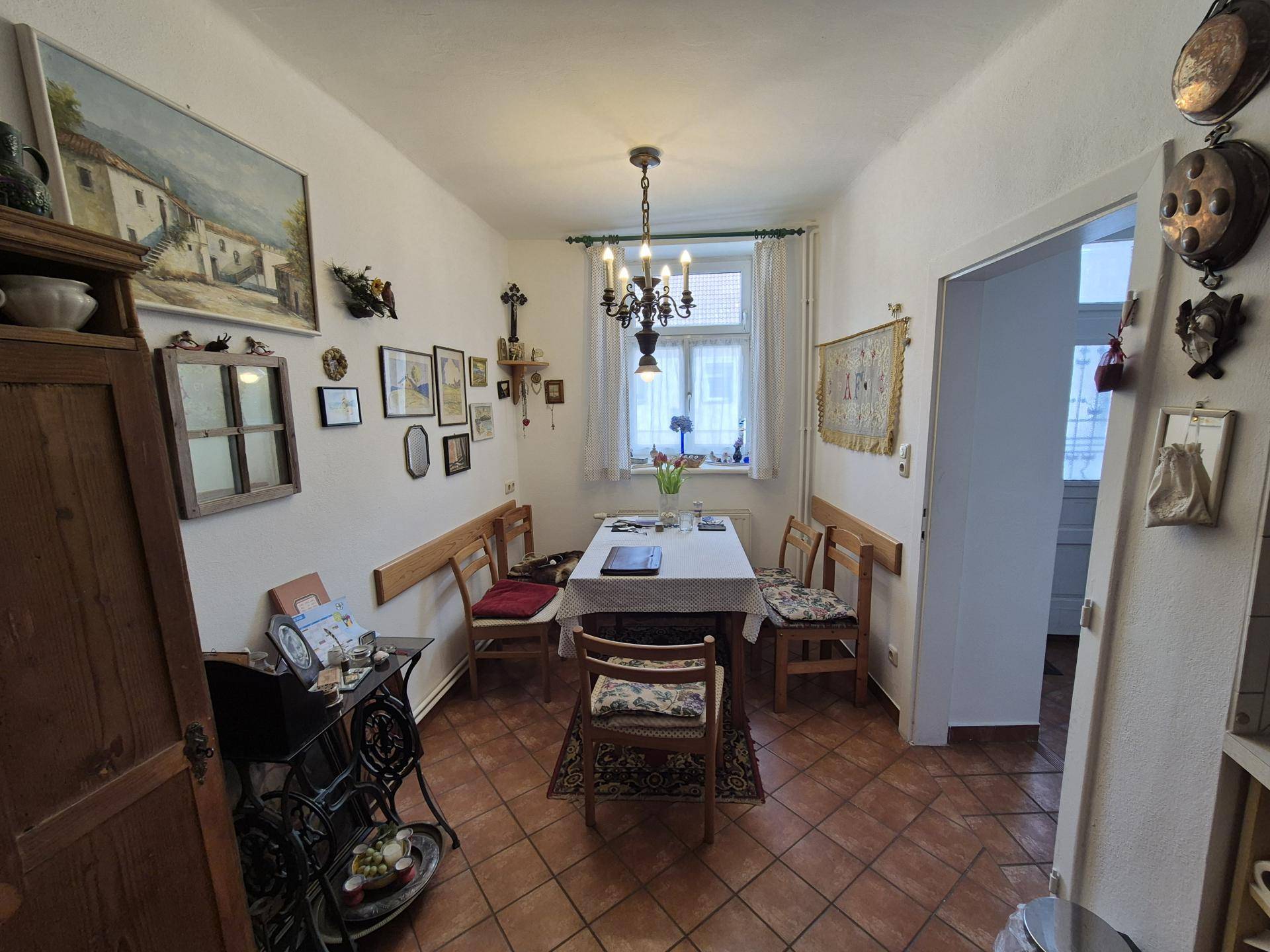 Helles Esszimmer mit Fliesenboden, Holztisch und Stühlen, ideal für gemeinsame Mahlzeiten.