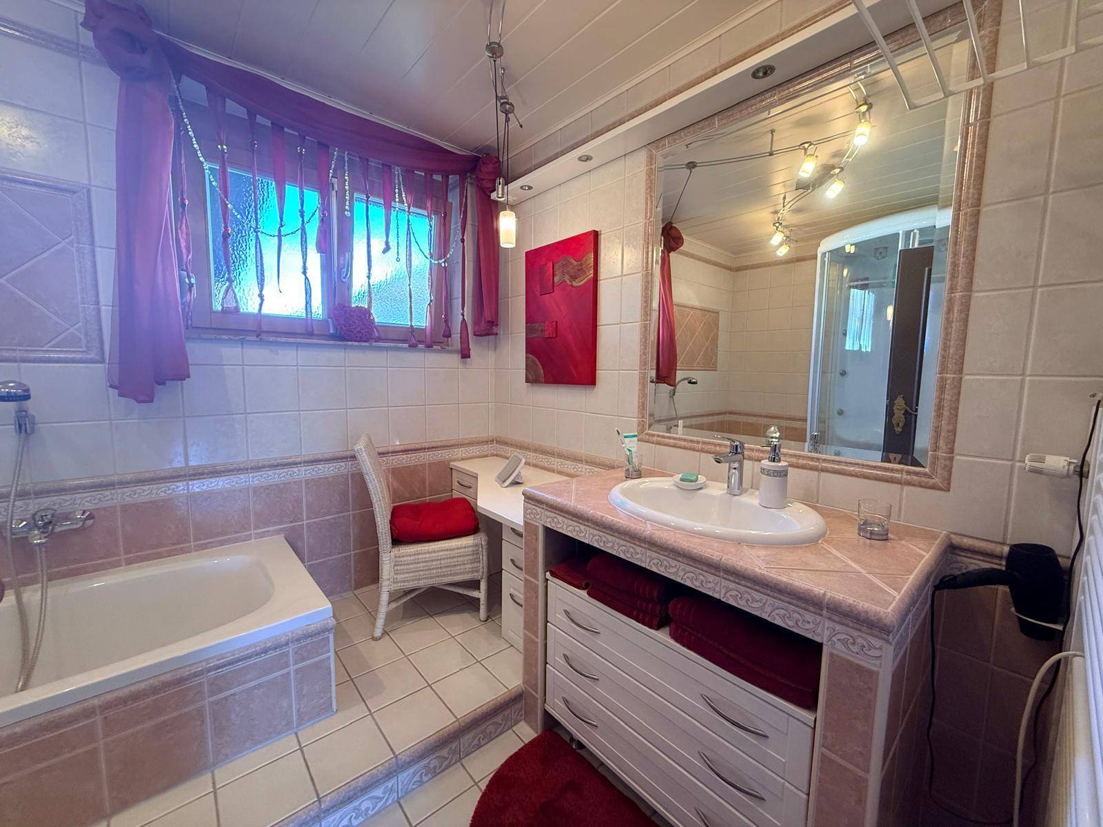 Badezimmer mit Badewanne, Einzelwaschbecken und rosa Fliesen im 80er-Jahre-Stil.