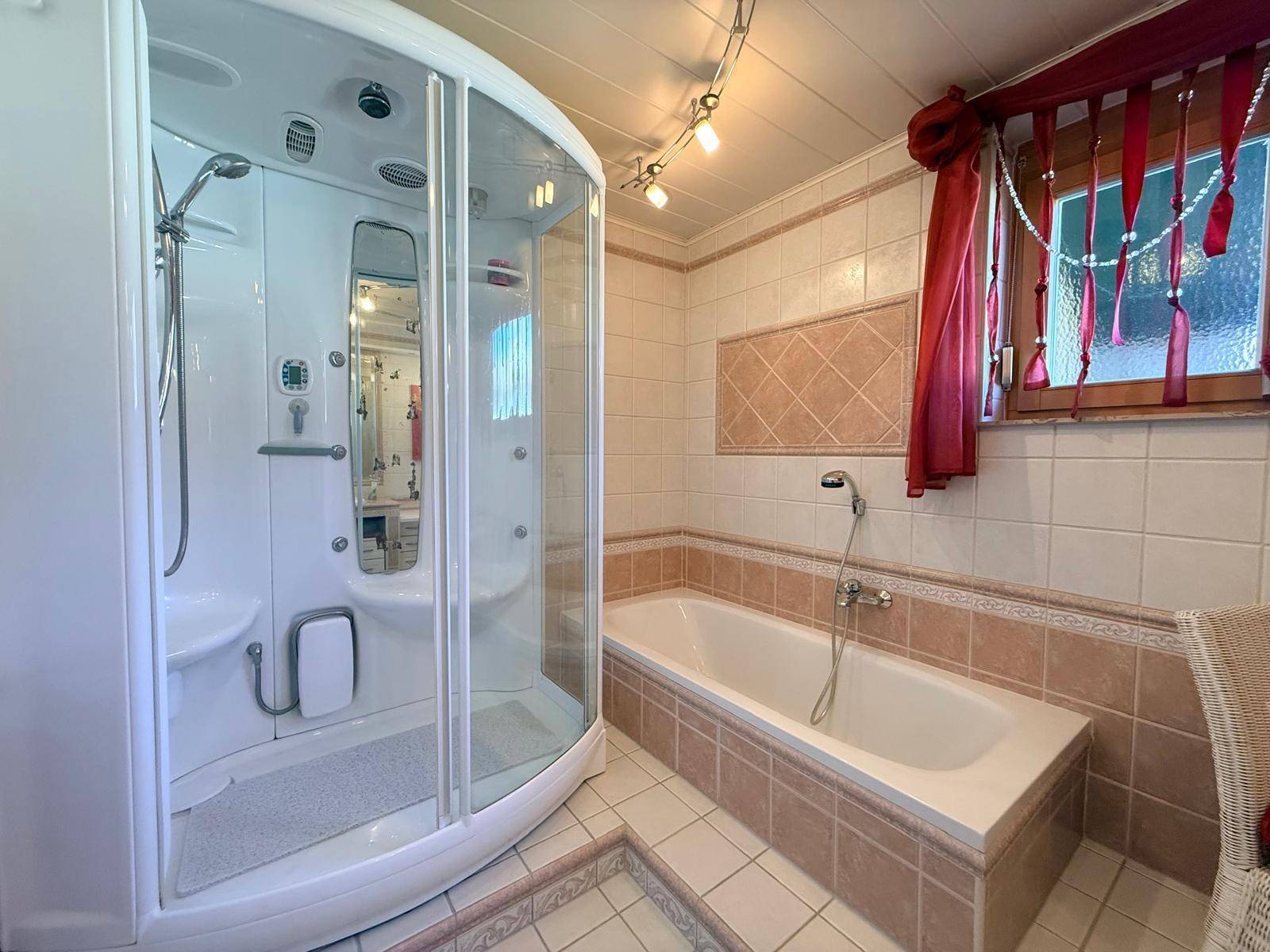 Badezimmer mit Duschkabine, Badewanne und rosa Fliesen im 80er-Jahre-Stil.