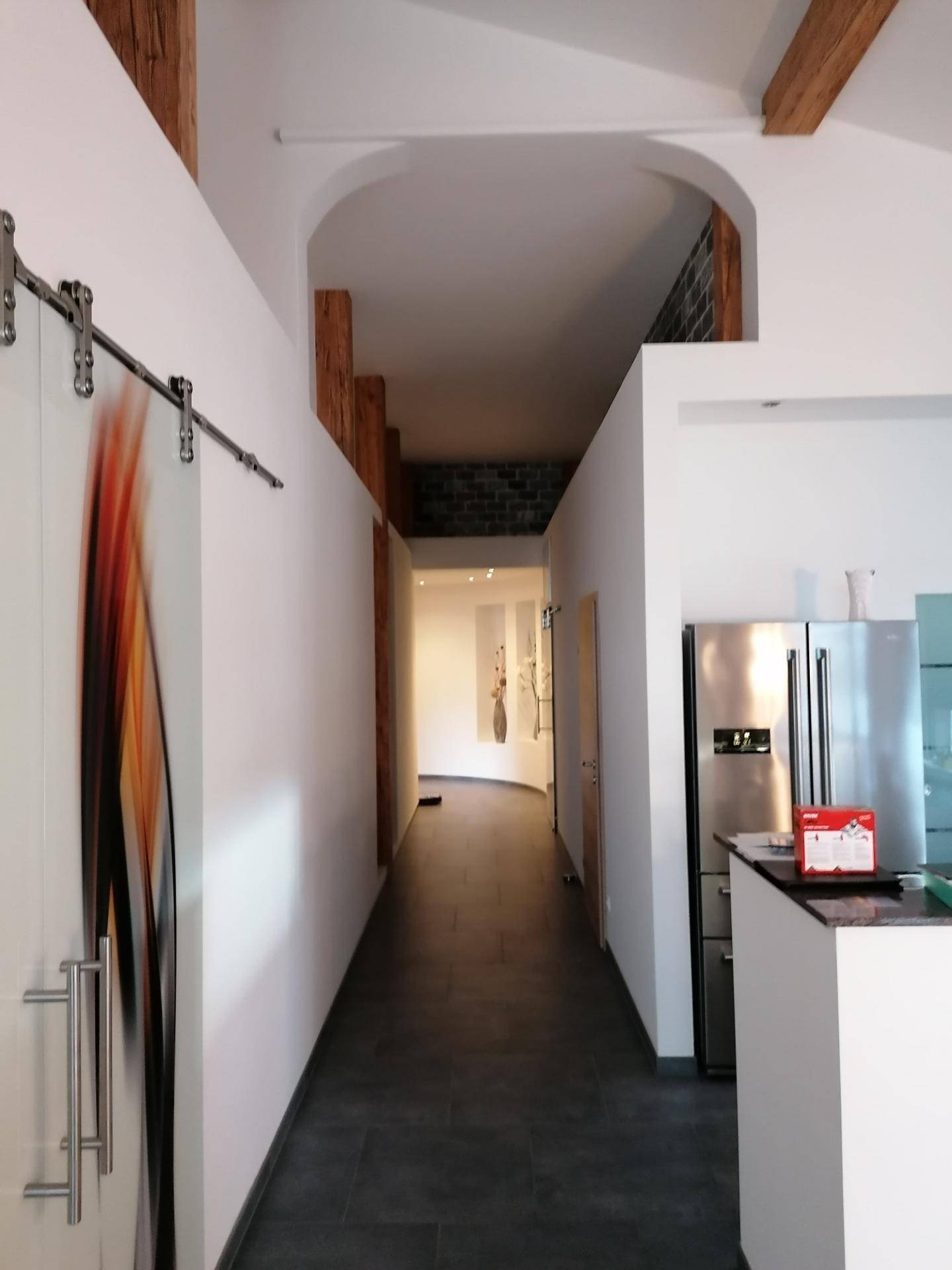 Moderner Flur mit Fliesenboden, sichtbaren Holzbalken und integriertem Kühlschrank, stilvoll und praktisch.