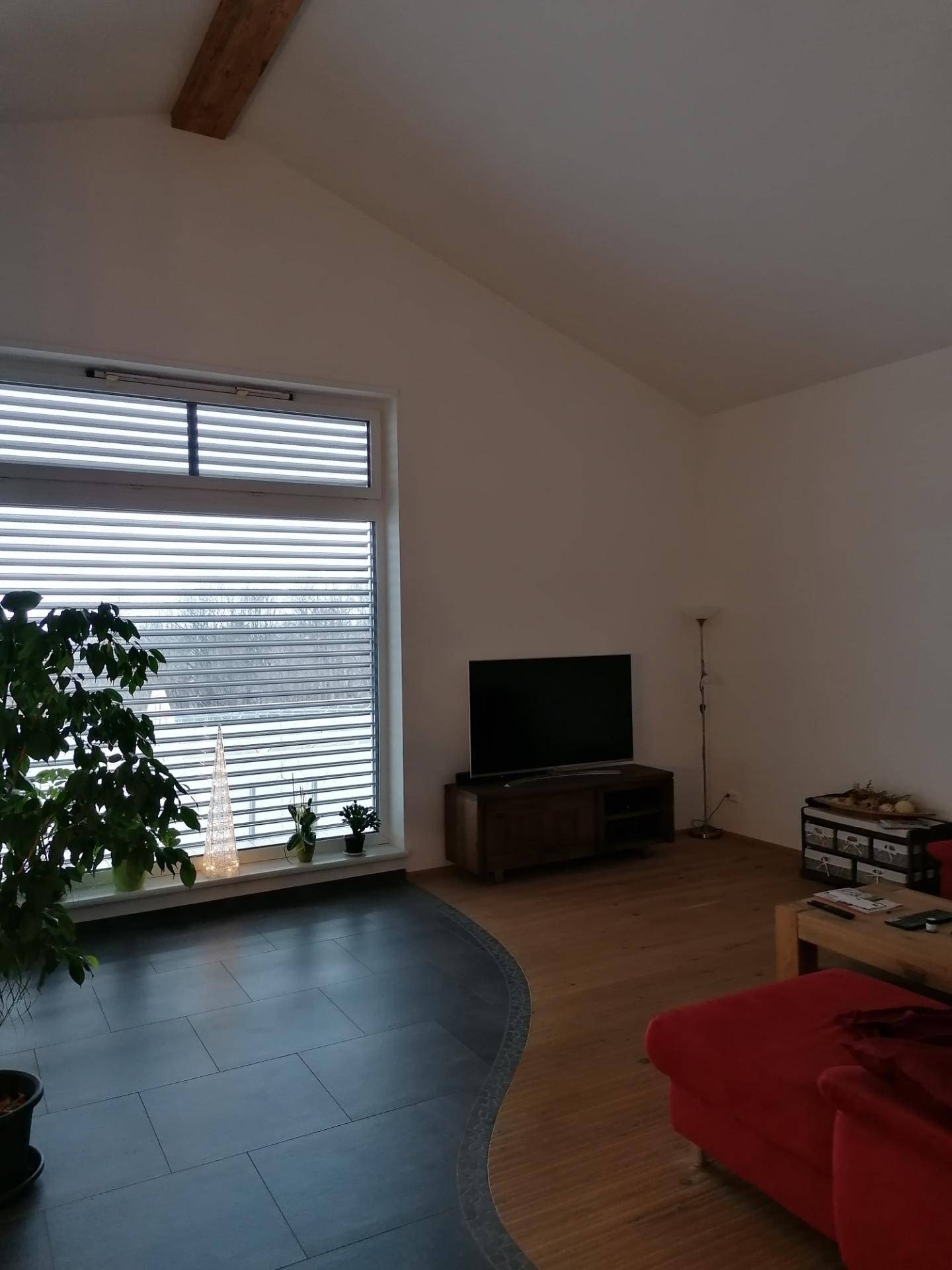 Geräumiges Wohnzimmer mit hohen Decken, großen Fenstern und Holzboden, lichtdurchflutet und modern.