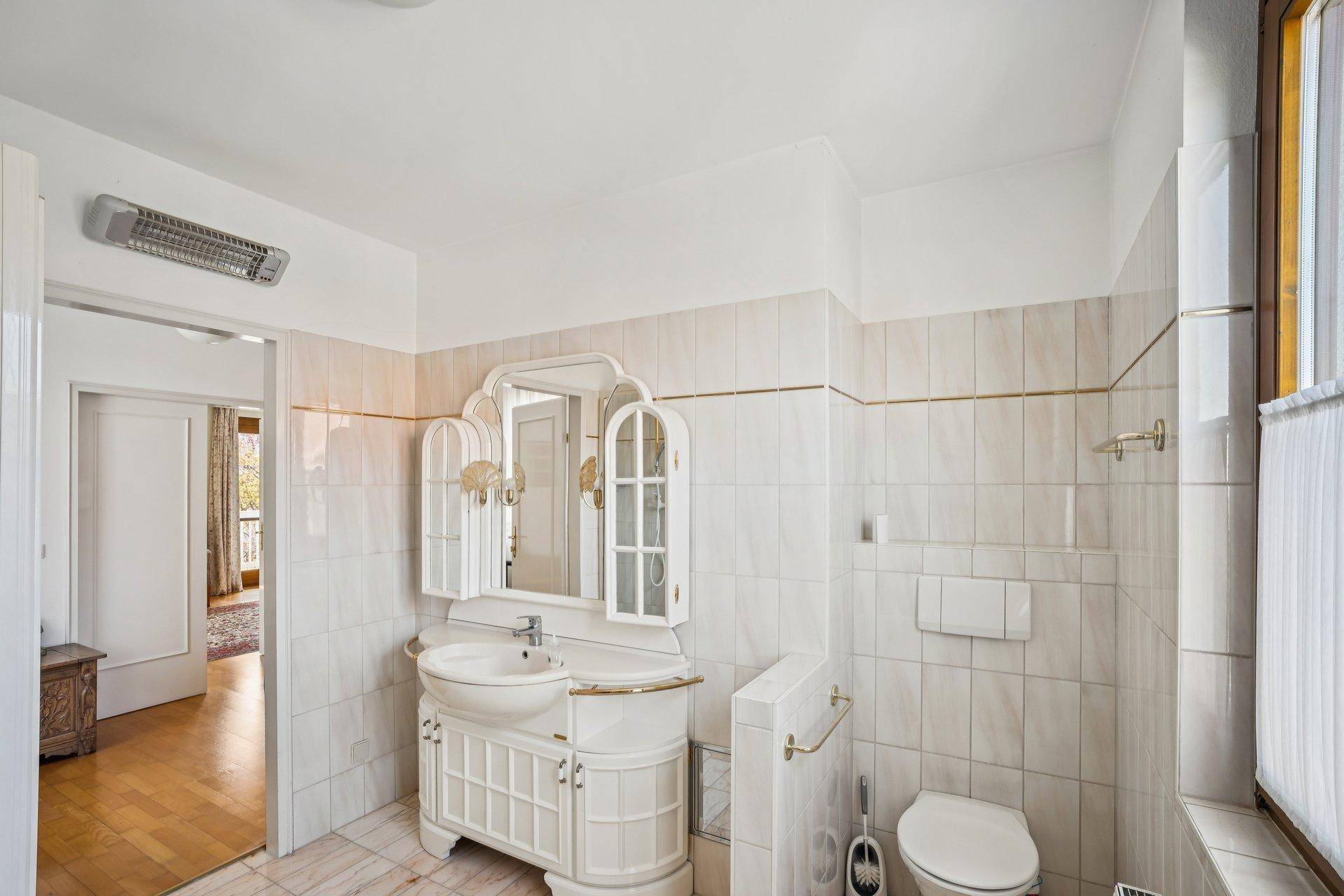 Badezimmer mit WC, Waschbeckenunterschrank und Spiegelkabinett in klassischem Stil.