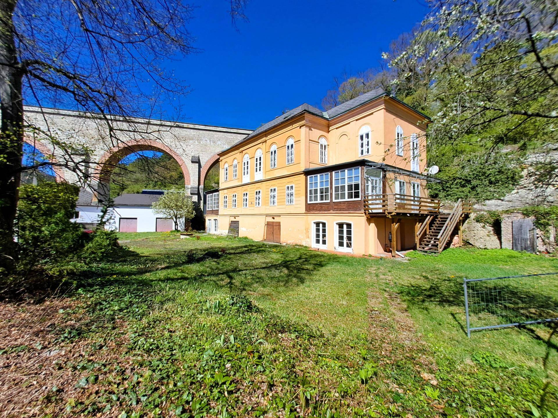 Weitläufige Ansicht des historischen Anwesens mit Viadukt und großem Gartenbereich.