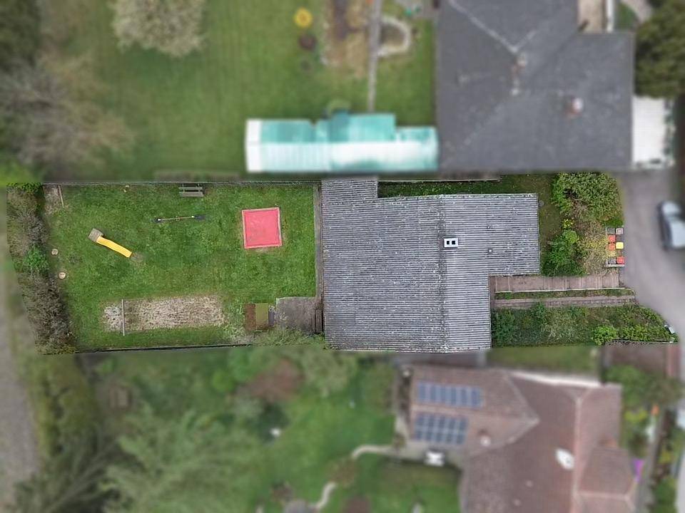 Senkrechte Luftaufnahme des Grundstücks mit Haus, Garten und Spielbereich, umgeben von Bäumen.