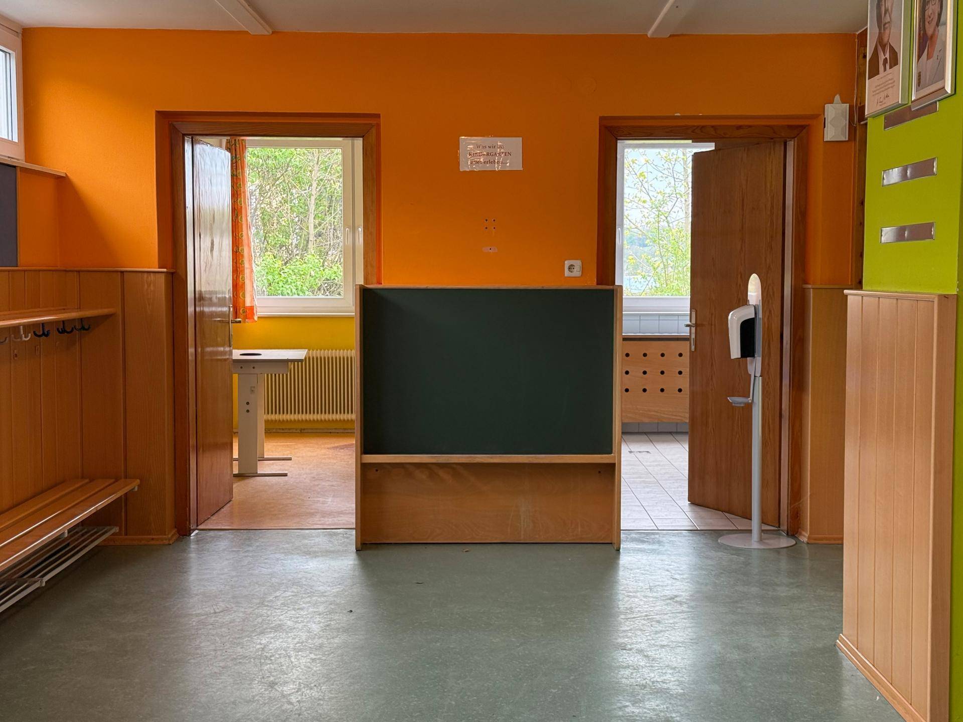 Übergangsbereich mit Tafel und Zugang zu hellen Räumen mit Blick ins Grüne.