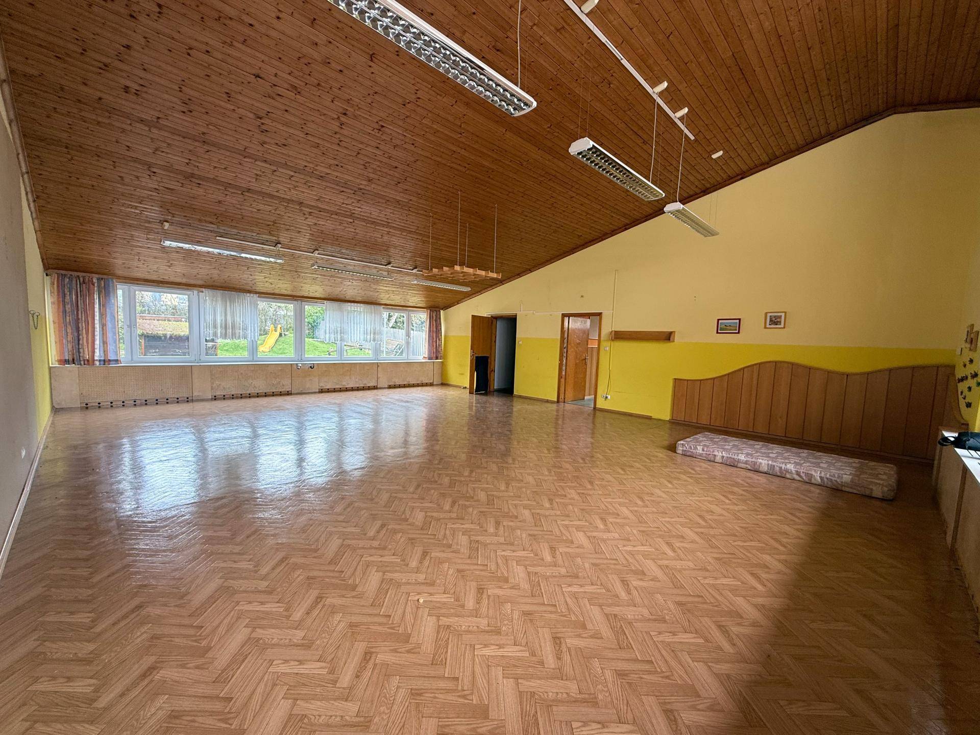 Heller und geräumiger Wohnbereich mit Holzdecke, Parkettboden und großen Fenstern für viel Tageslicht.