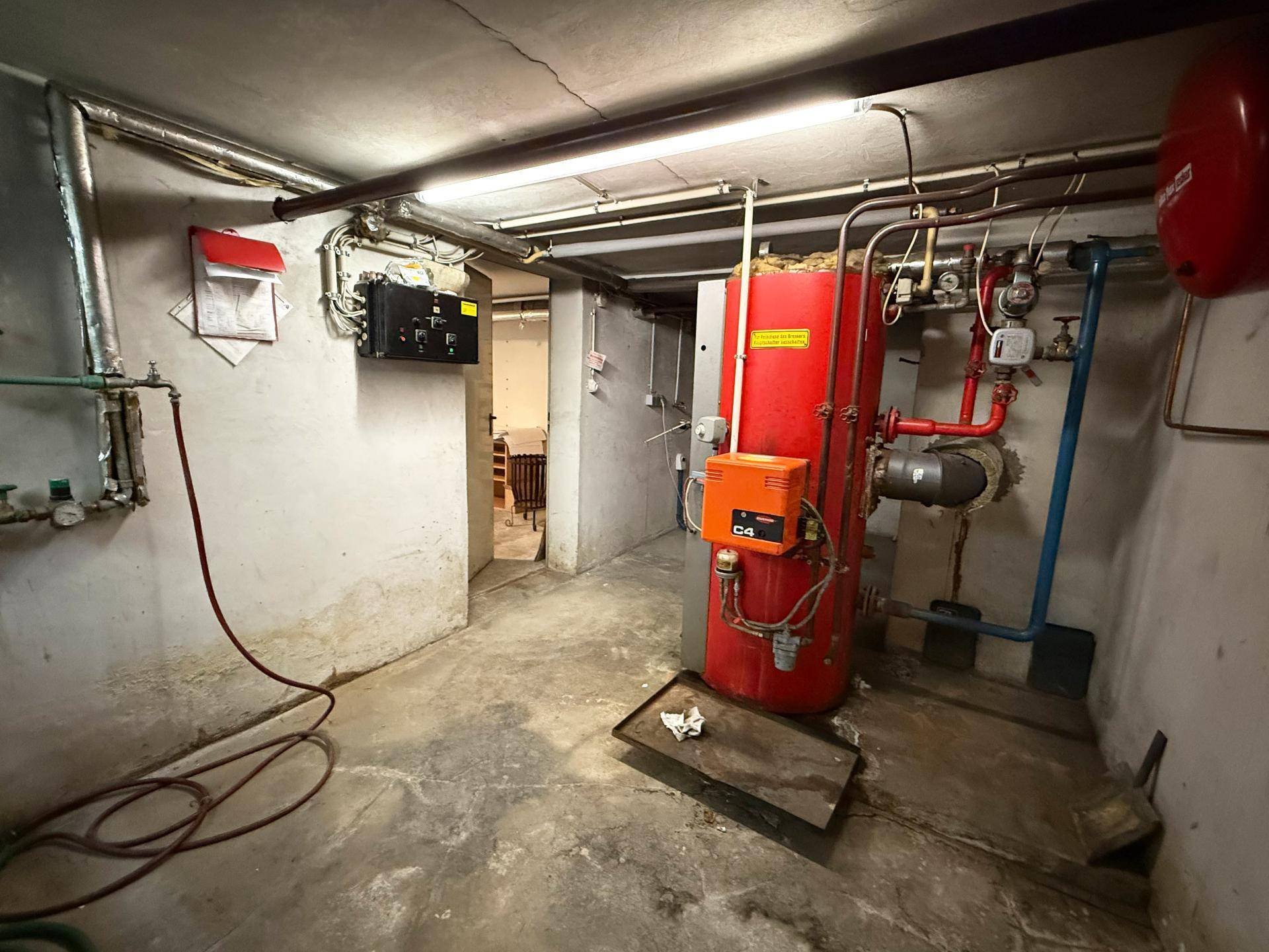 Heizungsraum im Keller mit Warmwasserspeicher und technischen Installationen für die Gebäudetechnik.