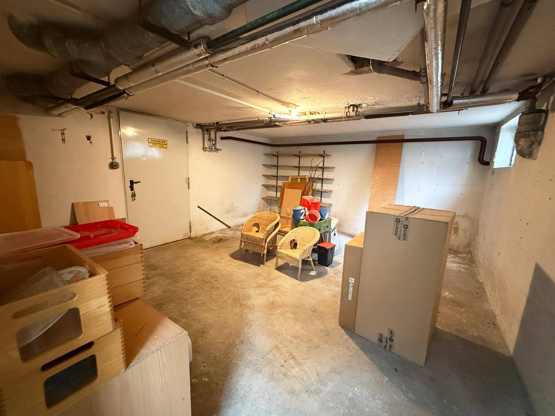 Geräumiger Kellerraum mit Betonboden, ideal für Lagerung und Hobbyaktivitäten, mit sichtbaren Rohren.