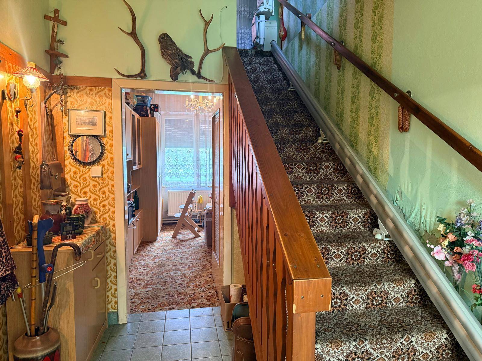 Flur mit Teppichtreppe, Holzgeländer und traditioneller Wandgestaltung mit Hirschgeweih.