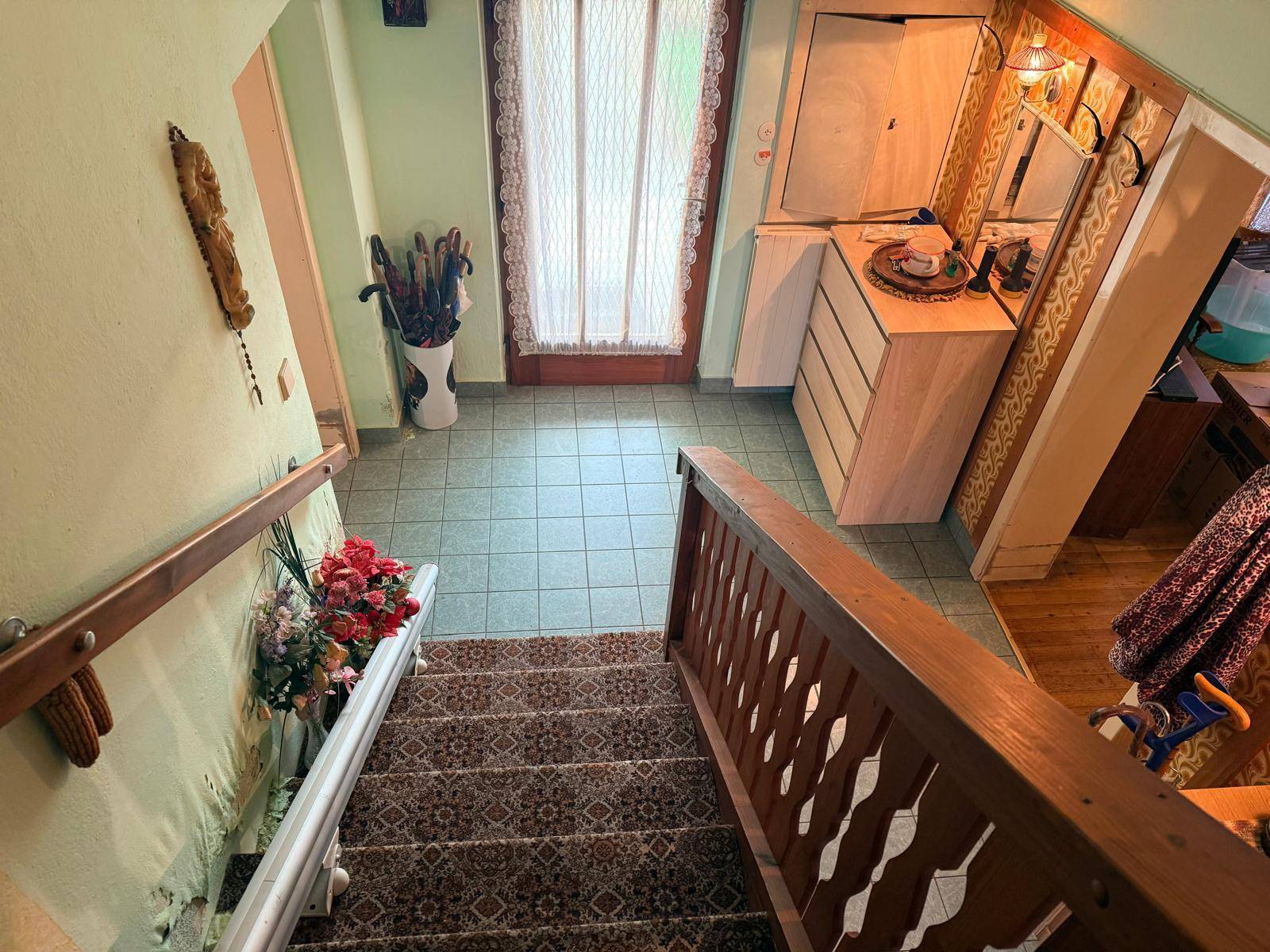 Eingangsbereich mit gefliestem Boden, Treppe und traditioneller Holzvertäfelung an den Wänden.