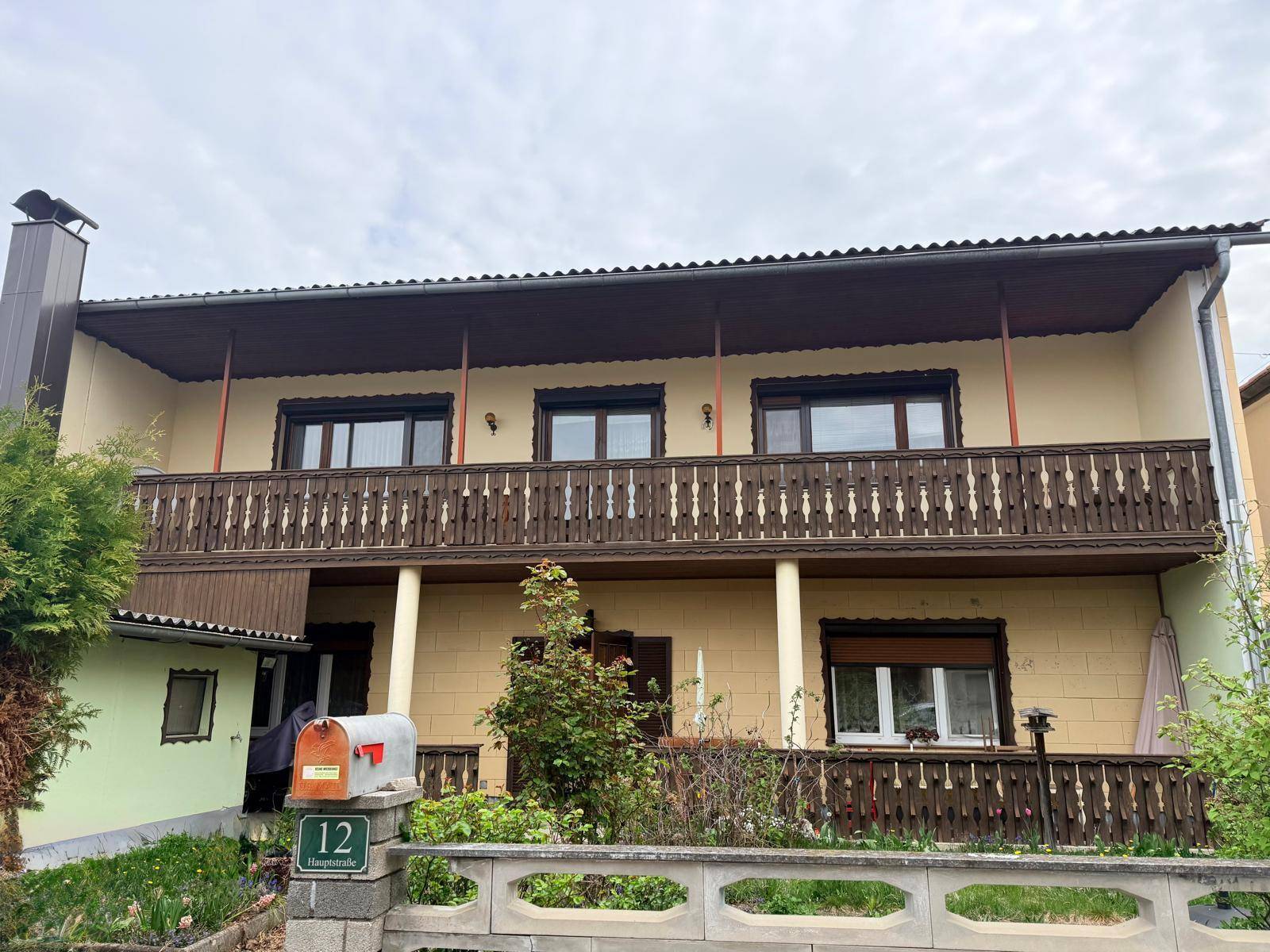 Vorderansicht des Hauses mit Balkon, Vorgarten und Briefkasten an der Straße.