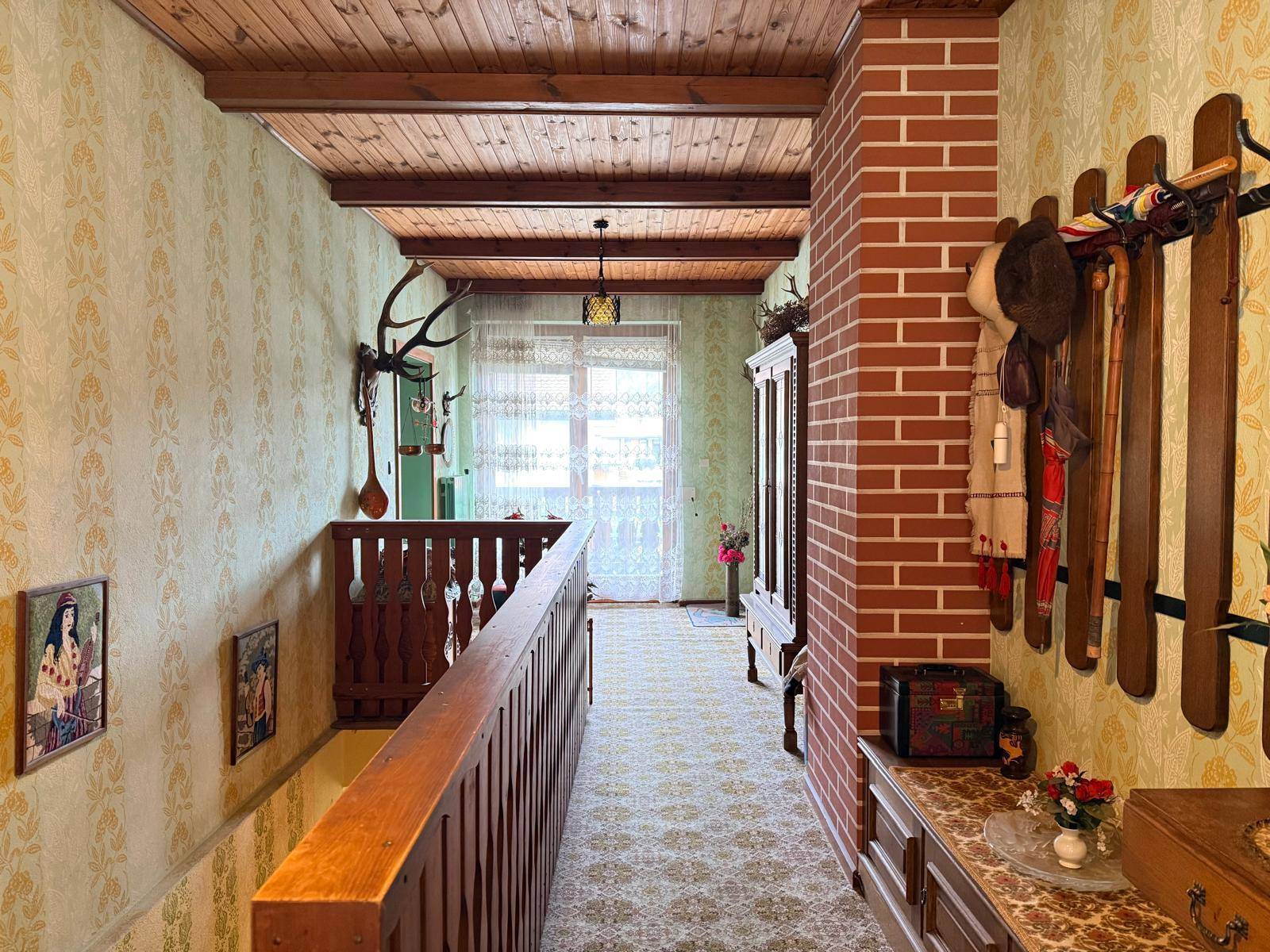Oberer Flur mit Holzdecke, Ziegelwand und traditioneller Dekoration inklusive Hirschgeweih.
