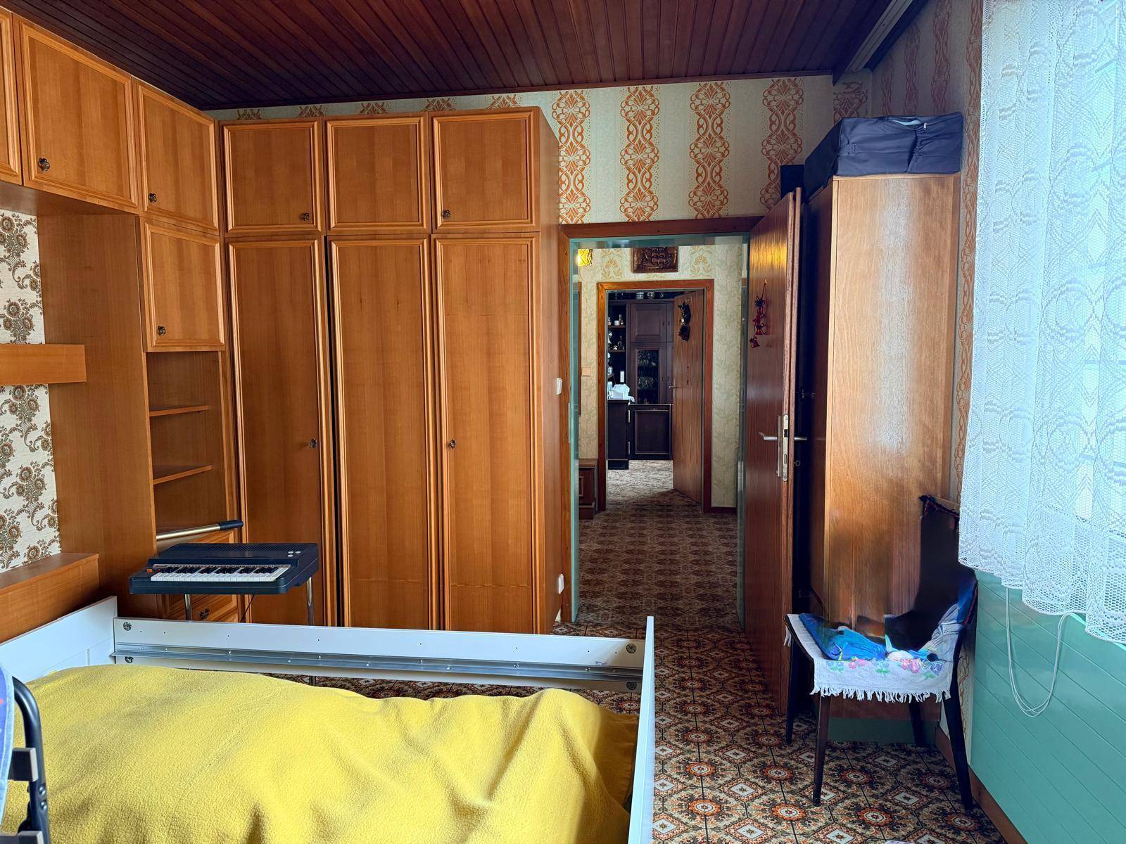 Schlafzimmer mit Einbauschränken, Holzbett und gemusterter Tapete im traditionellen Stil.