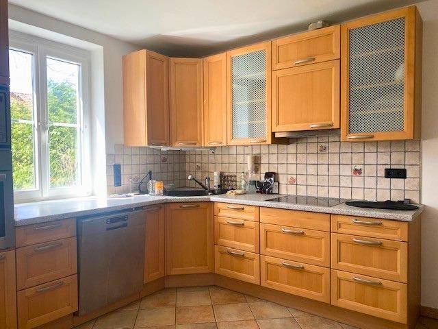 Funktionale Küche mit hellen Holzschränken, Spülmaschine und Fenster für Tageslicht.