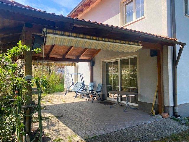 Überdachte Terrasse mit Markise, Gartenmöbeln und Zugang zum Innenbereich des Hauses.