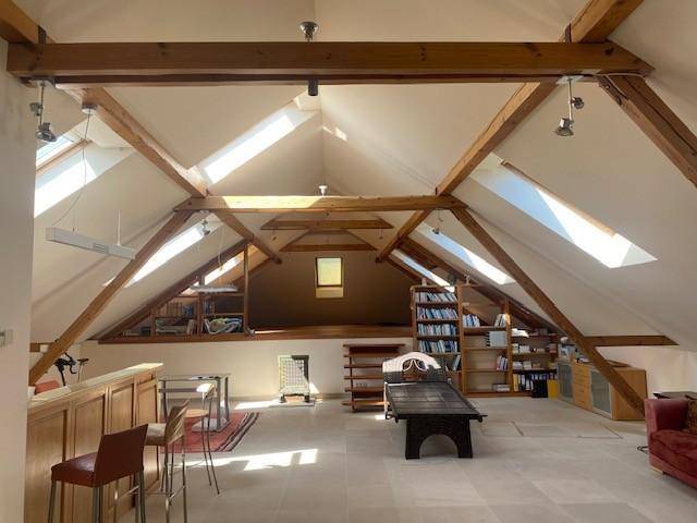 Heller Dachbodenraum mit sichtbaren Holzbalken, Dachfenstern und vielseitigen Nutzungsmöglichkeiten.