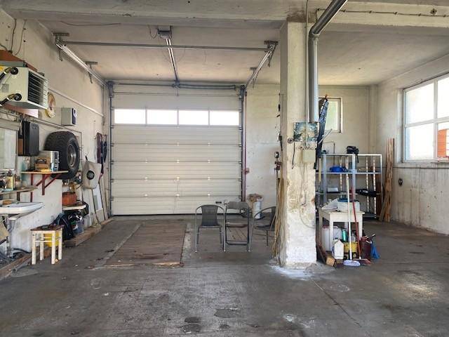 Geräumige Garage mit großem Rolltor, Werkstattbereich und Fenstern.