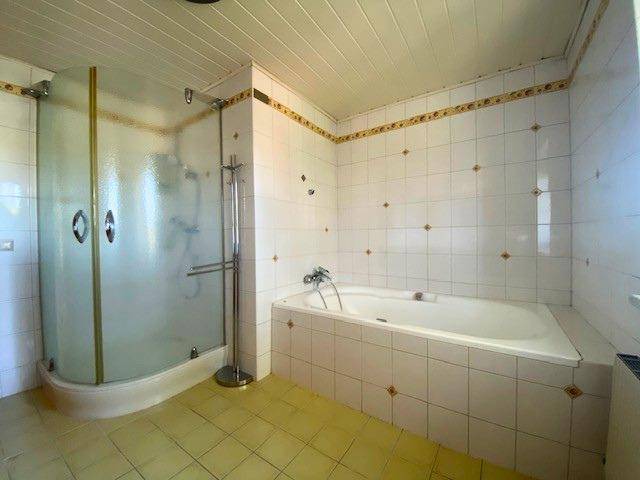 Geräumiges Badezimmer mit Duschkabine, Eckbadewanne und Fliesenboden in heller Farbgebung.